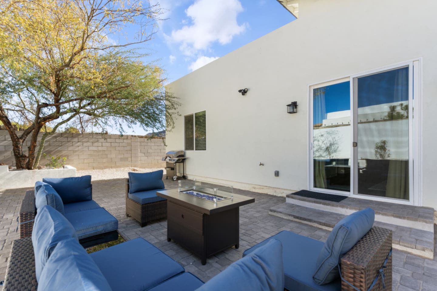 Outdoor living space with comfortable seating, grill, and a fire pit table for evening downtime.