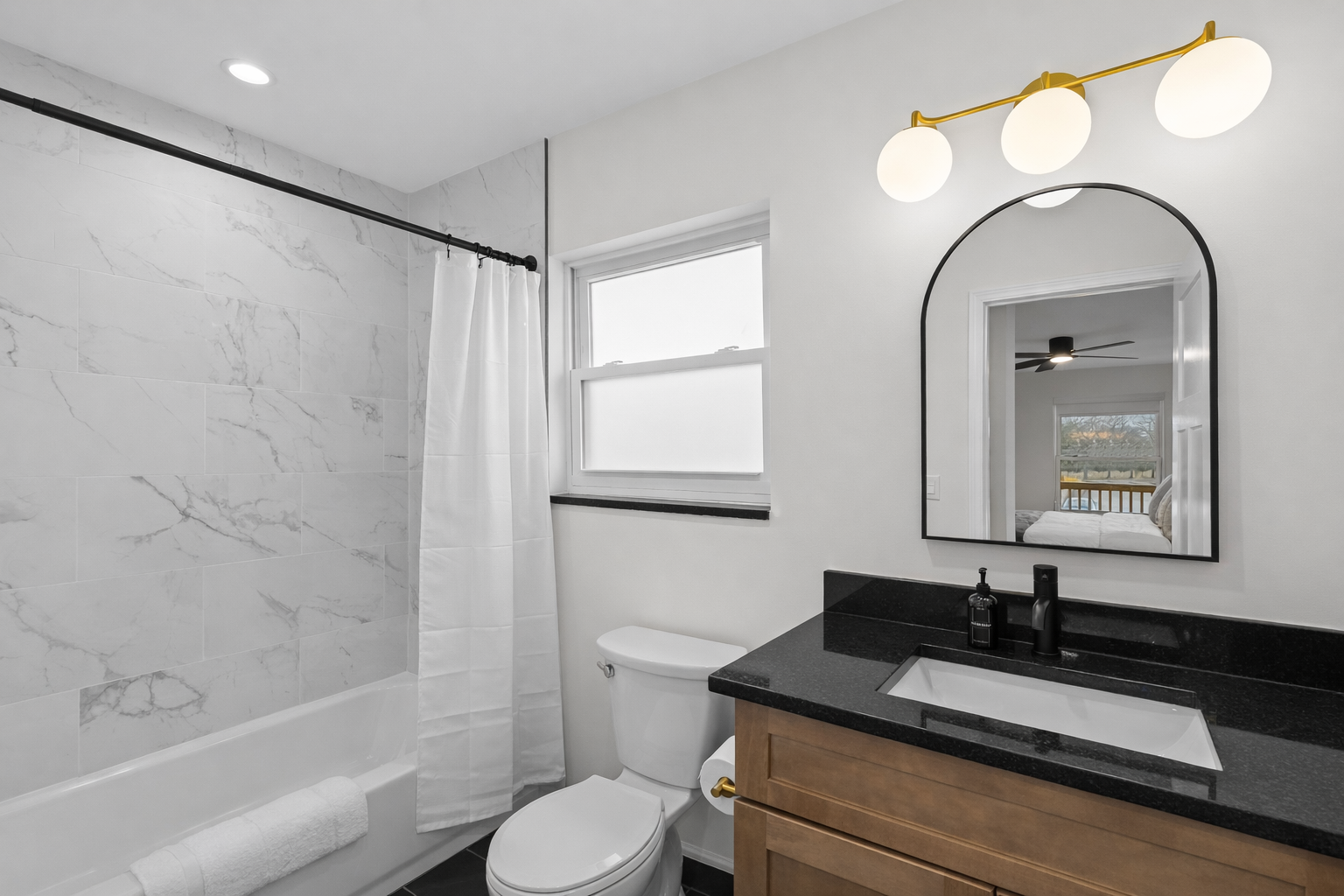 Clean, modern bathroom with a tiled tub/shower, sleek vanity, and bright lighting—designed for a refreshing, comfortable stay.