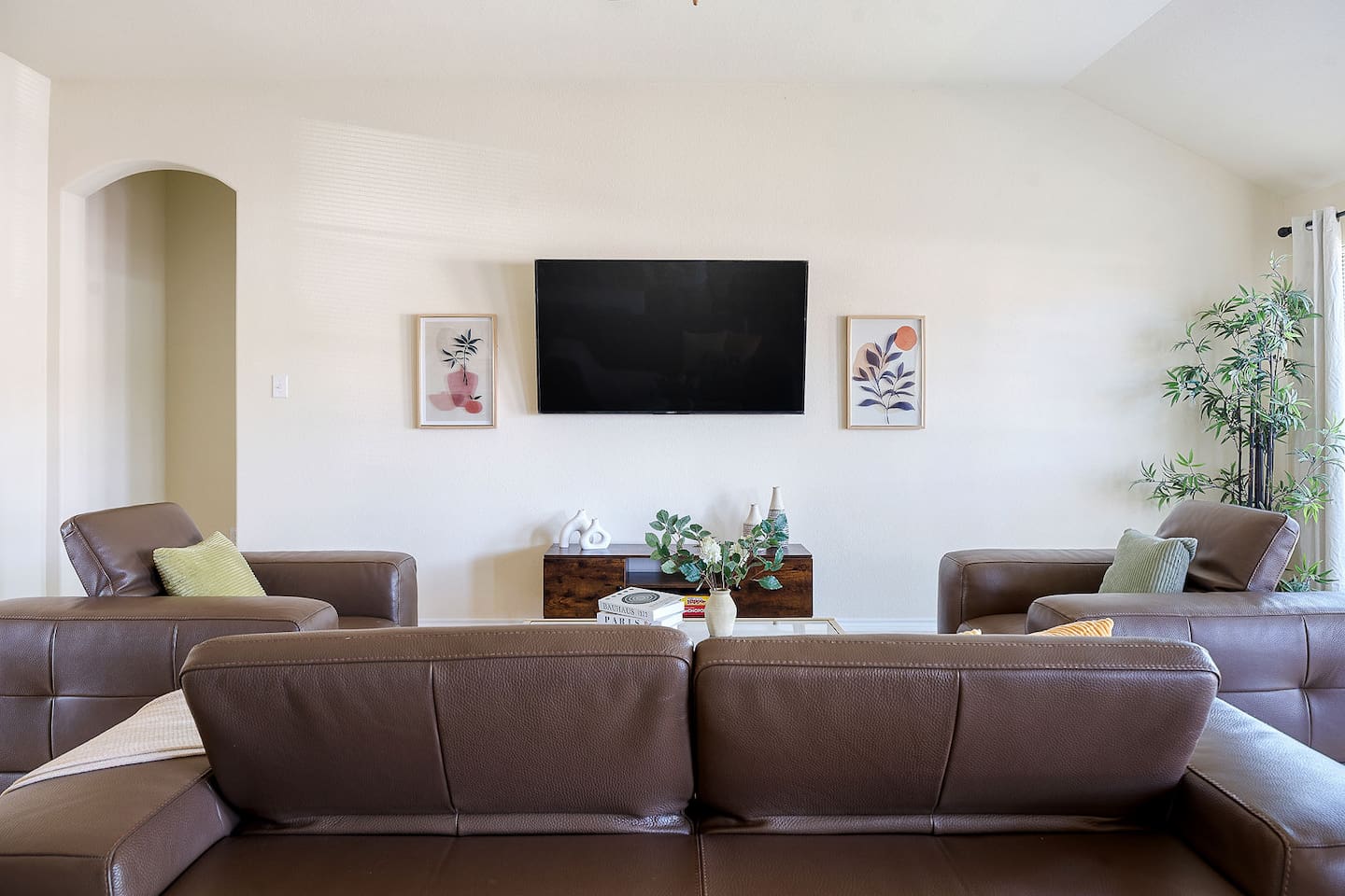 Experience the comfort of this elegant living room, featuring plush leather sofas and a large wall-mounted TV.