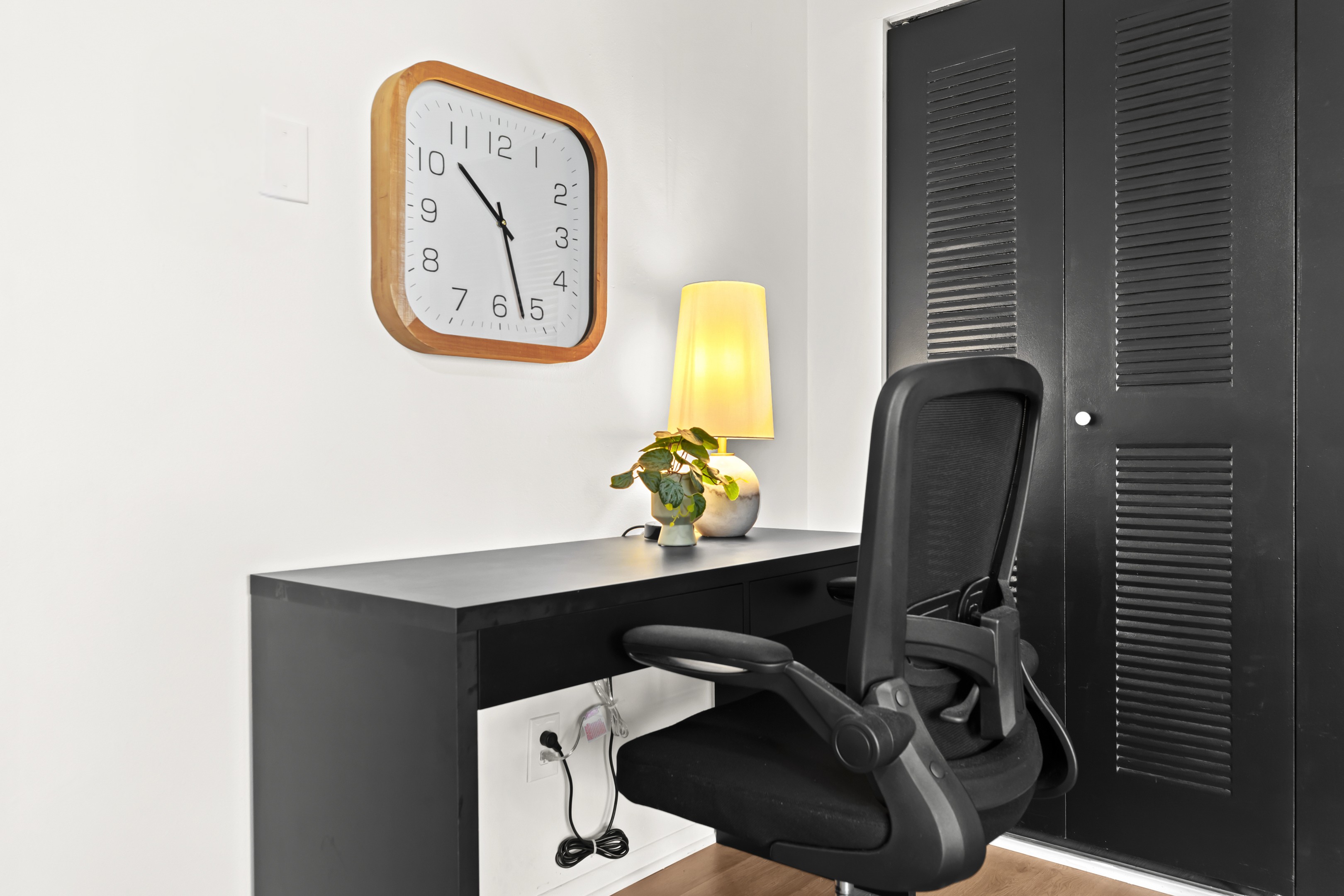 Well-lit workstation with desk, ergonomic chair, and charging access—ready for productivity.
