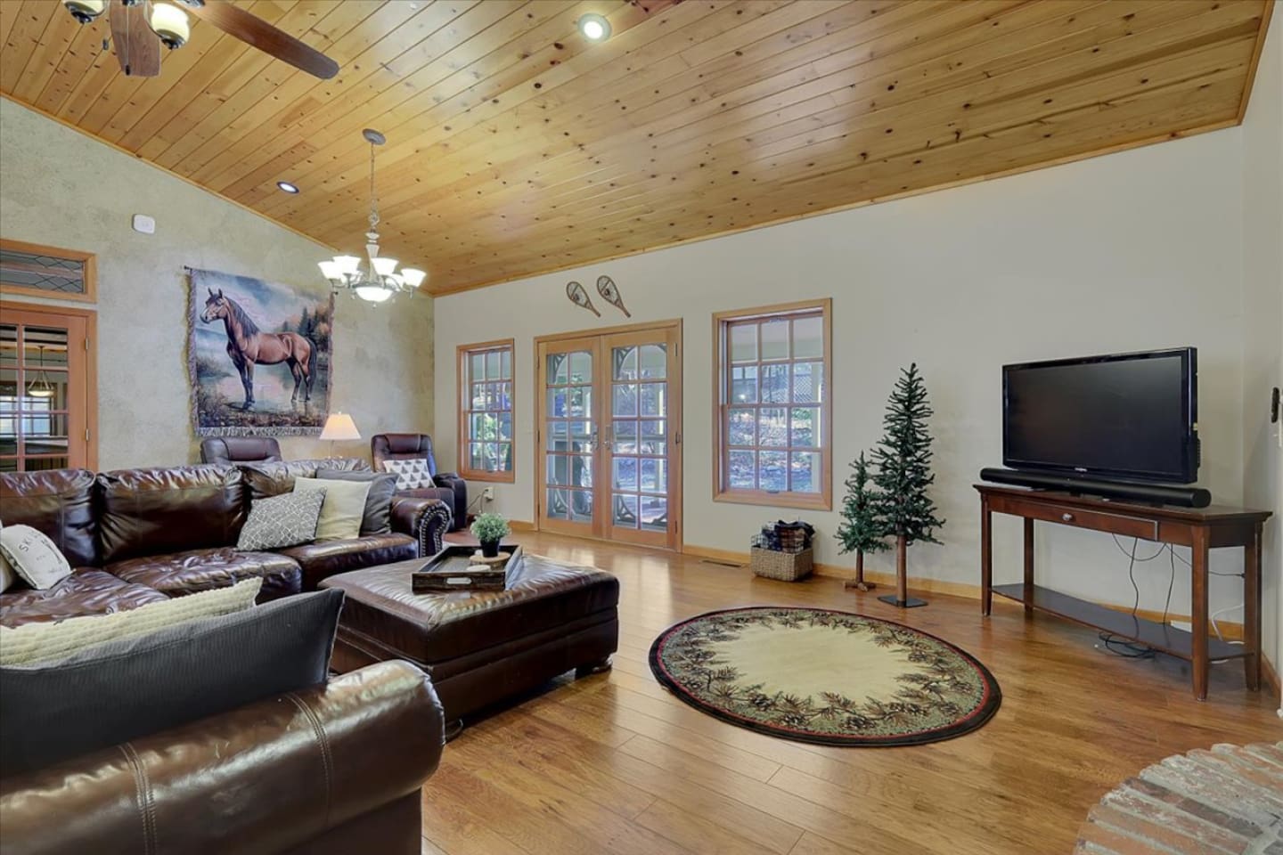 Living room with leather seating, wood ceilings, TV, and a relaxed cozy feel.
