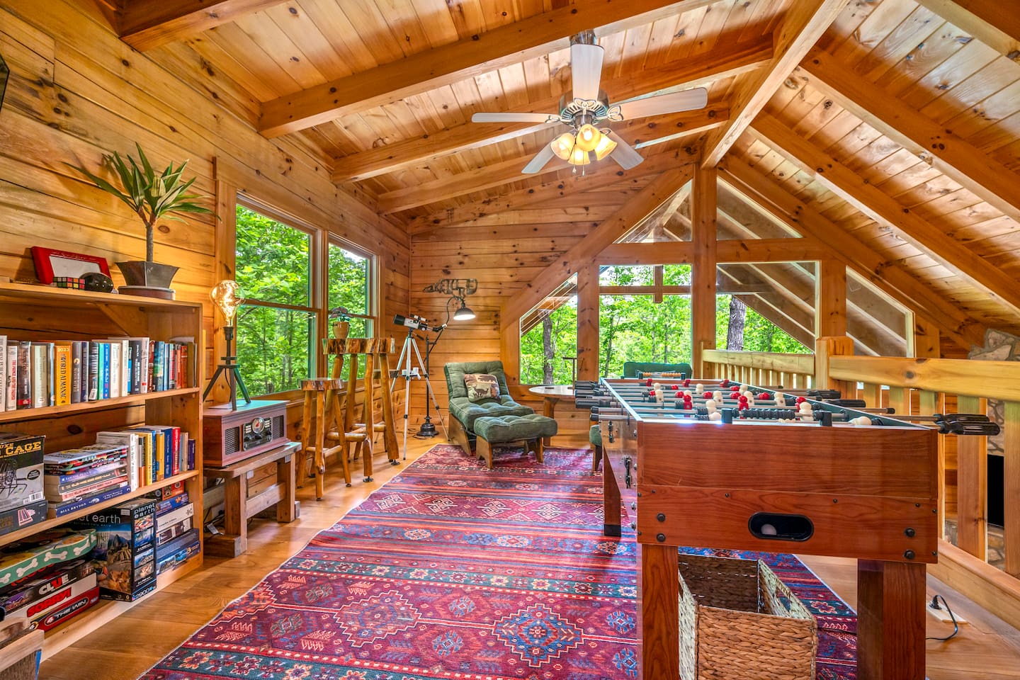 Loft game area with foosball table, reading nook, board games, and peaceful treetop views. The perfect upstairs retreat for family fun and relaxing cabin nights.