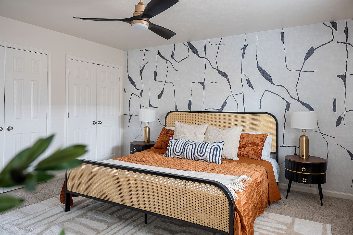 Relax in this trendy bedroom, which features a comfortable bed and one-of-a-kind wall decor. A ceiling fan creates a comfortable environment.