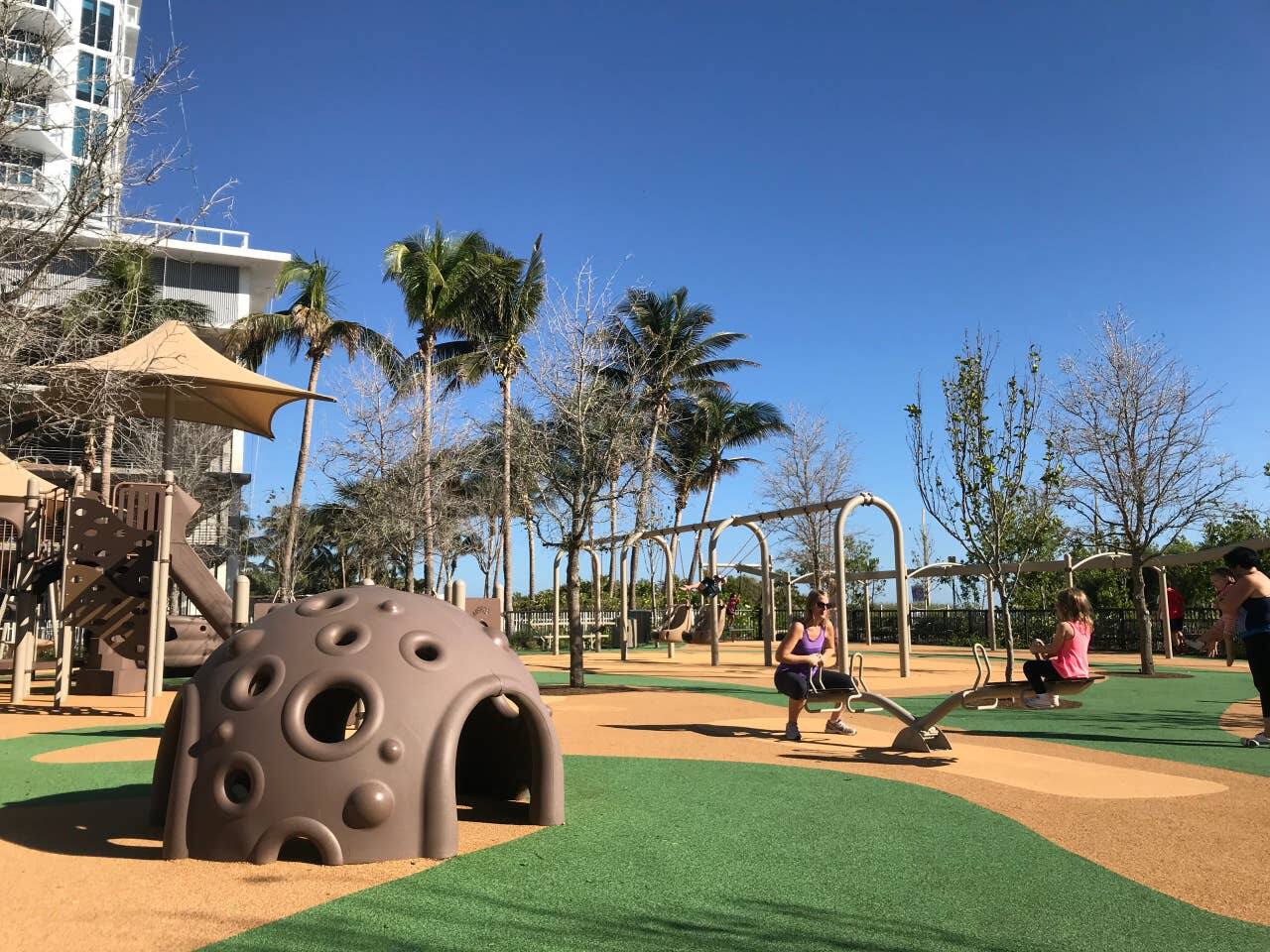 Beach playground at Allison Park with sun shades and a zipline, kids run safely while parents take a breather