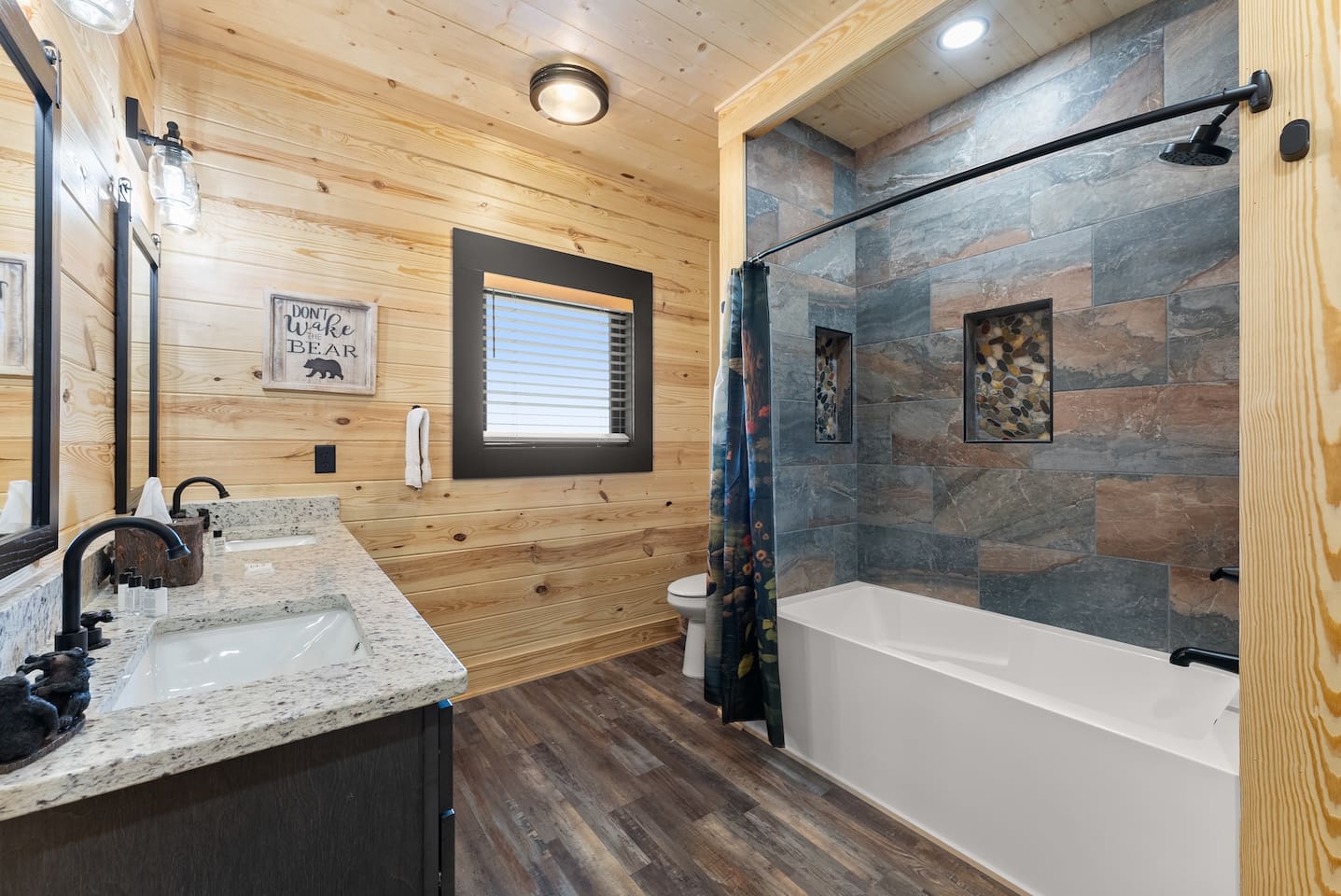 Rustic charm meets convenience in this third full bathroom, featuring a double vanity with granite counters and black fixtures.