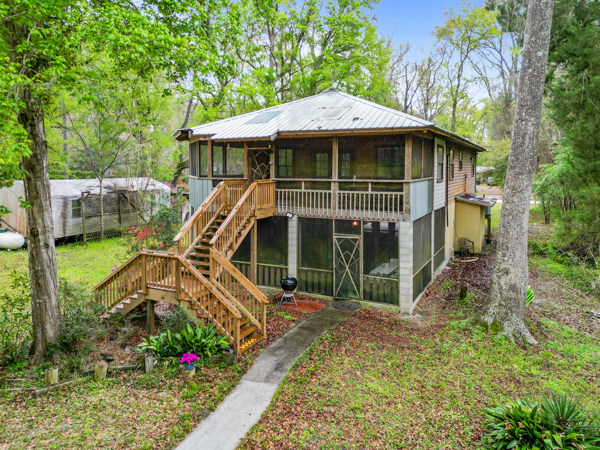 Back view of cabin with screen porches and pathway leading to the river. 