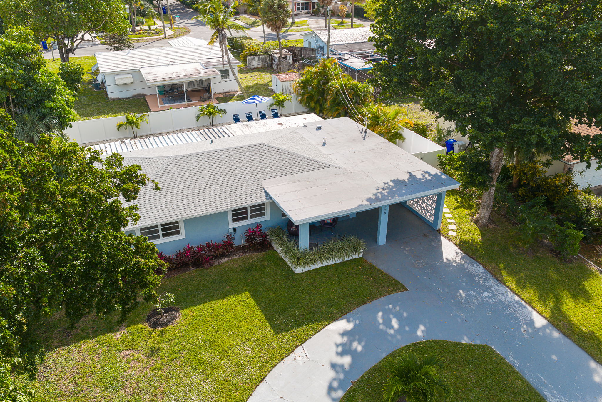 Soaring aerial perspectives highlight the home’s tranquil Pompano Beach neighborhood, private backyard oasis, covered carport, and extended driveway with space for 3 cars.