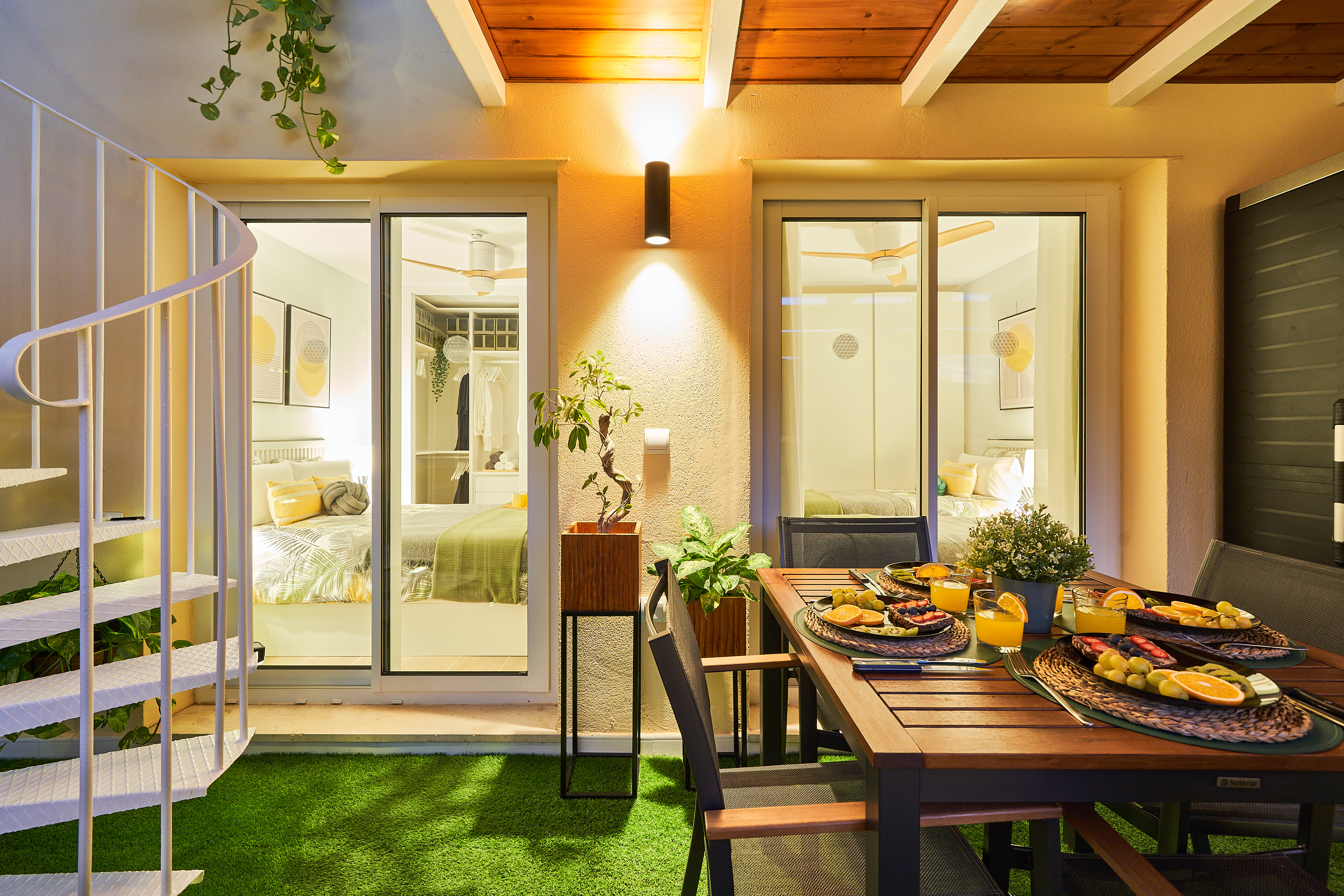 Private covered balcony with dining area, lush plants, and ambient lighting — ideal for a relaxed breakfast or a cozy evening meal.