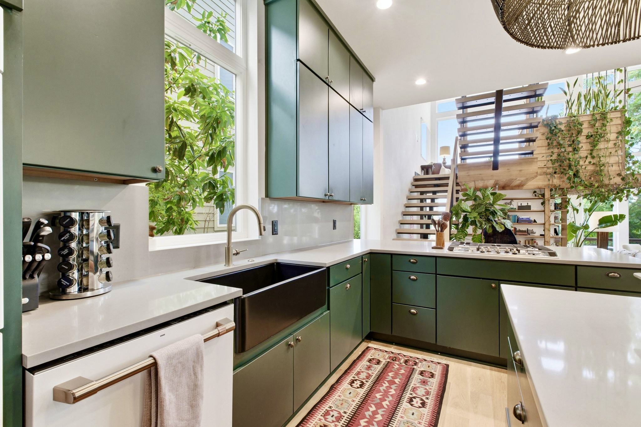 Expansive green kitchen w/ dual-tone cabinetry, sink & bright windows flooding the space w/ light.

