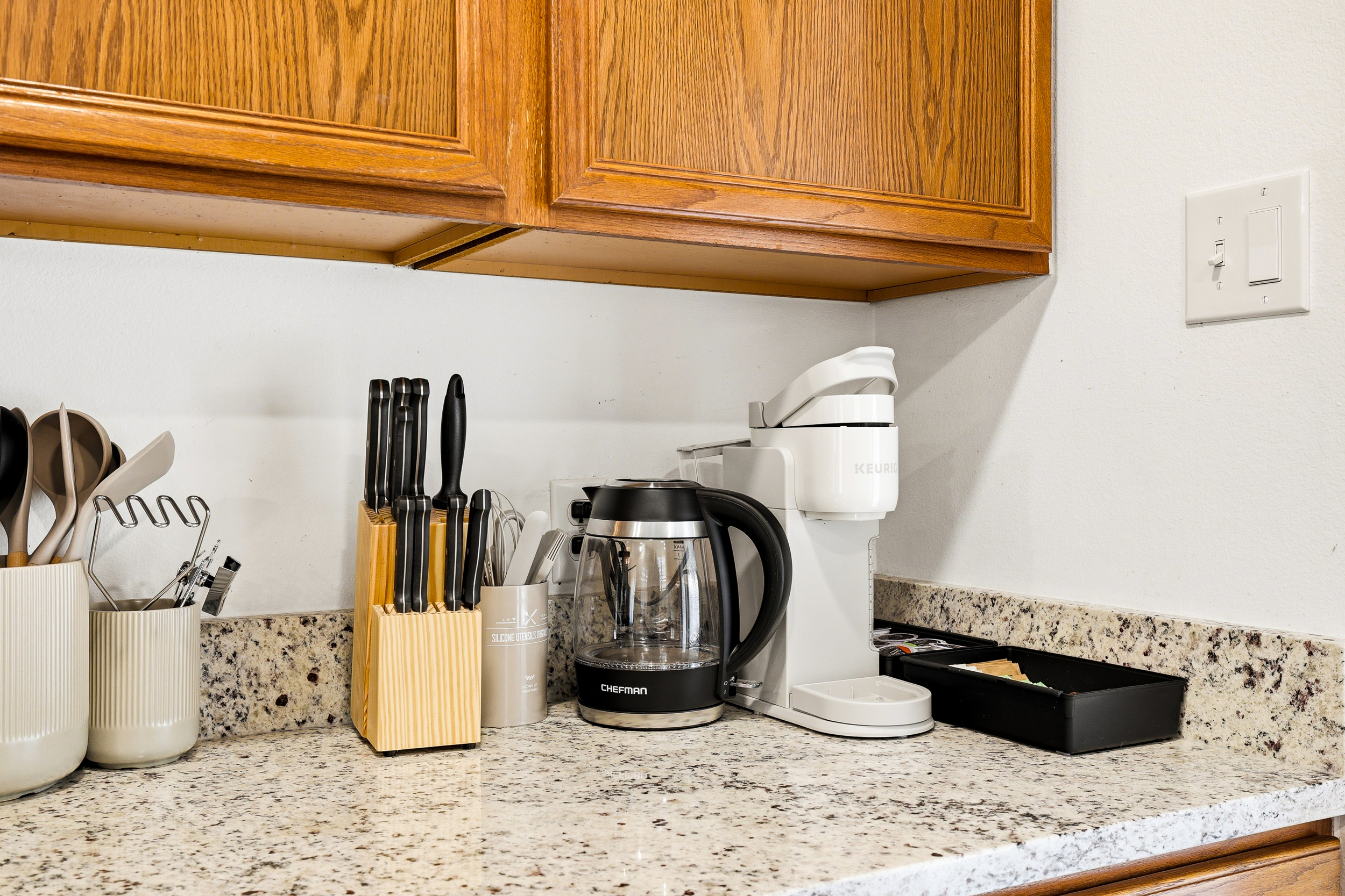 Kitchen counter stocked with Keurig coffee maker, hot water kettle, full knife set, and cooking utensils — everything within reach for your morning routine or full home-cooked meals.