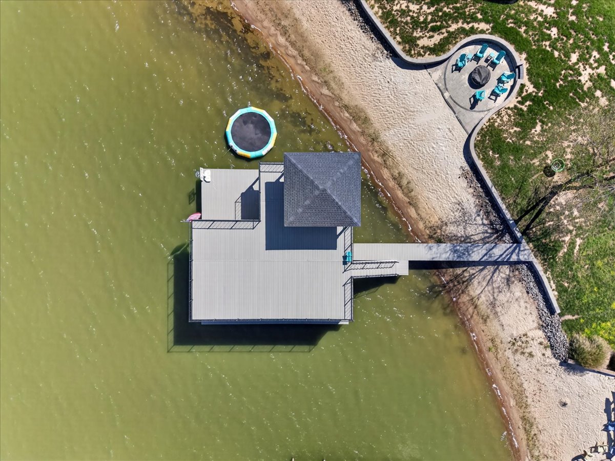 Bird’s-eye view of the boathouse, sandy beach, firepit area, and waterfront recreation space.