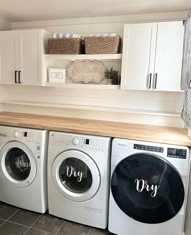 This bright laundry room features high-efficiency washer and dryers with a spacious butcher block folding counter. This well-appointed area includes overhead storage and shelving, making it easy to enjoy fresh towels and linens during your beach vacation.