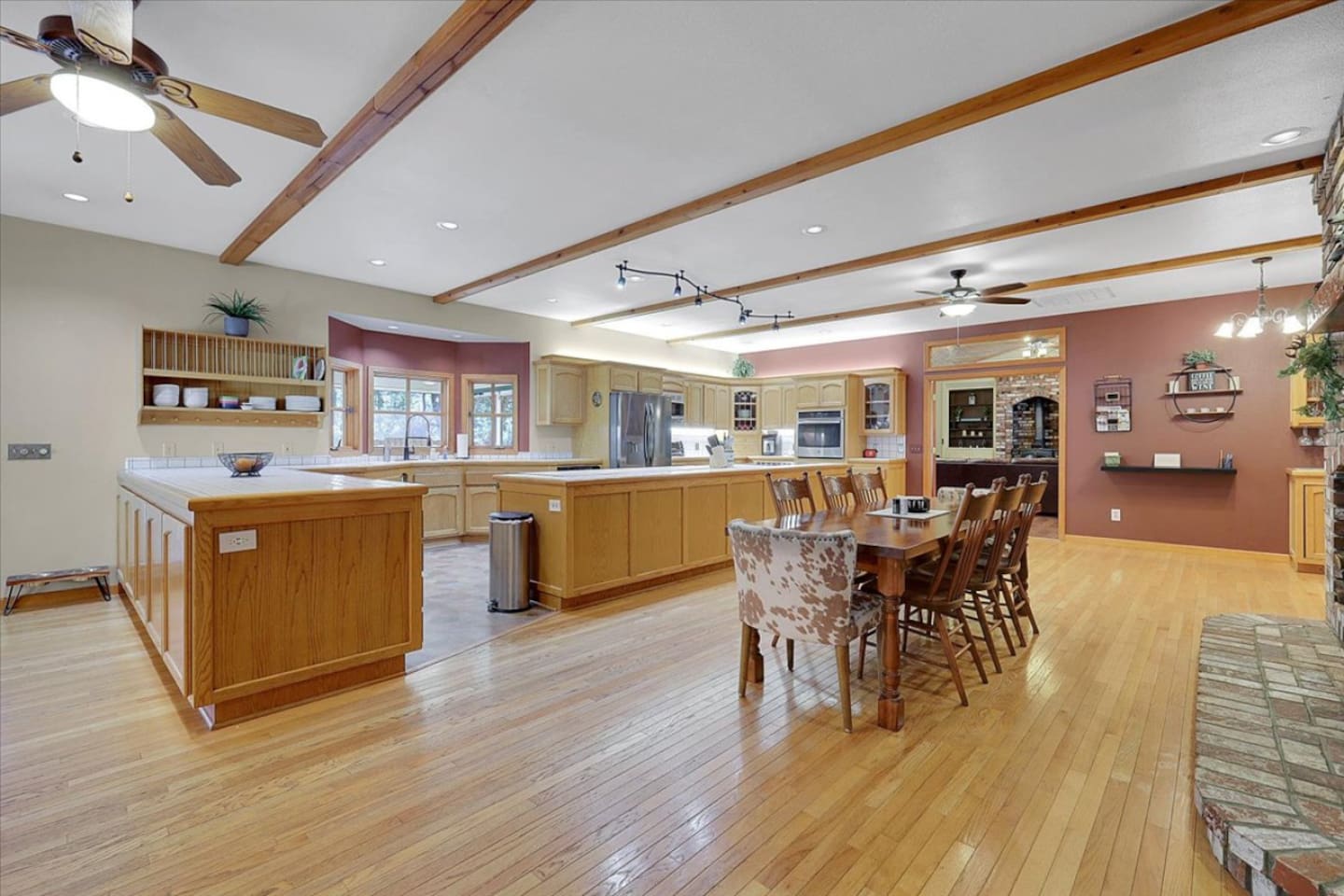 Open kitchen and dining area with lots of counter space, wood floors, and a brick fireplace nearby.
