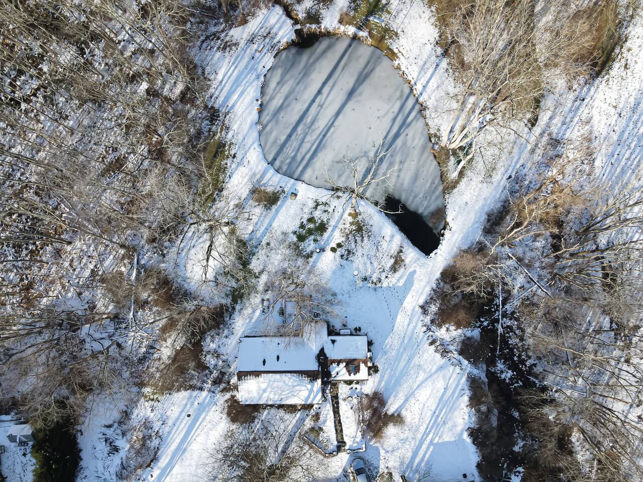 Higher altitude drone shot of pond, house and driveway.