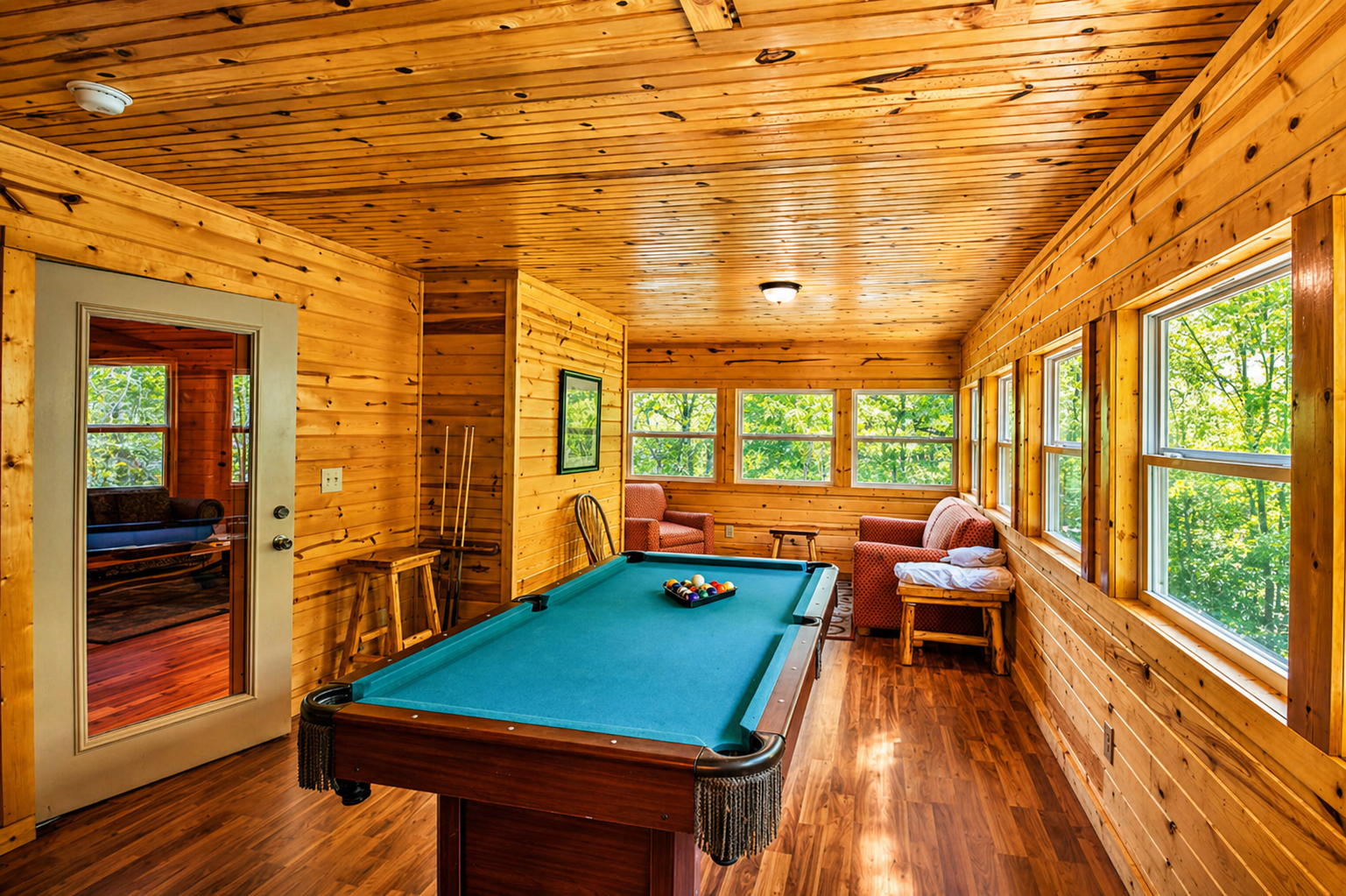Game room vibes with a classic pool table, sunlit windows, and cozy seating—perfect for friendly competition and laid-back cabin nights.