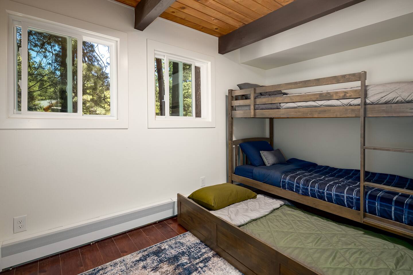 Fun & Functional – A sturdy three-bed bunk setup with a hidden pull-out trundle makes this space perfect for kids or extra guests.  