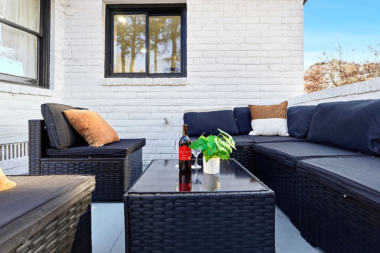 Inviting patio with black outdoor furniture, beige chairs, and a propane grill. A great space to relax, dine outside, or enjoy time with friends and family.