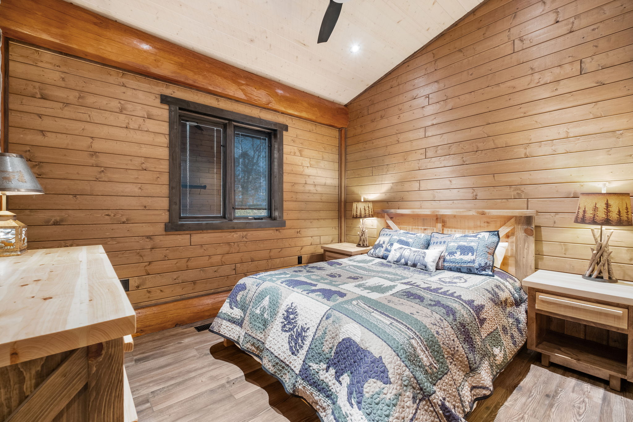 Comfortable queen bedroom with modern rustic décor, large window, and handcrafted wooden furnishings — bright, spacious, and calming.