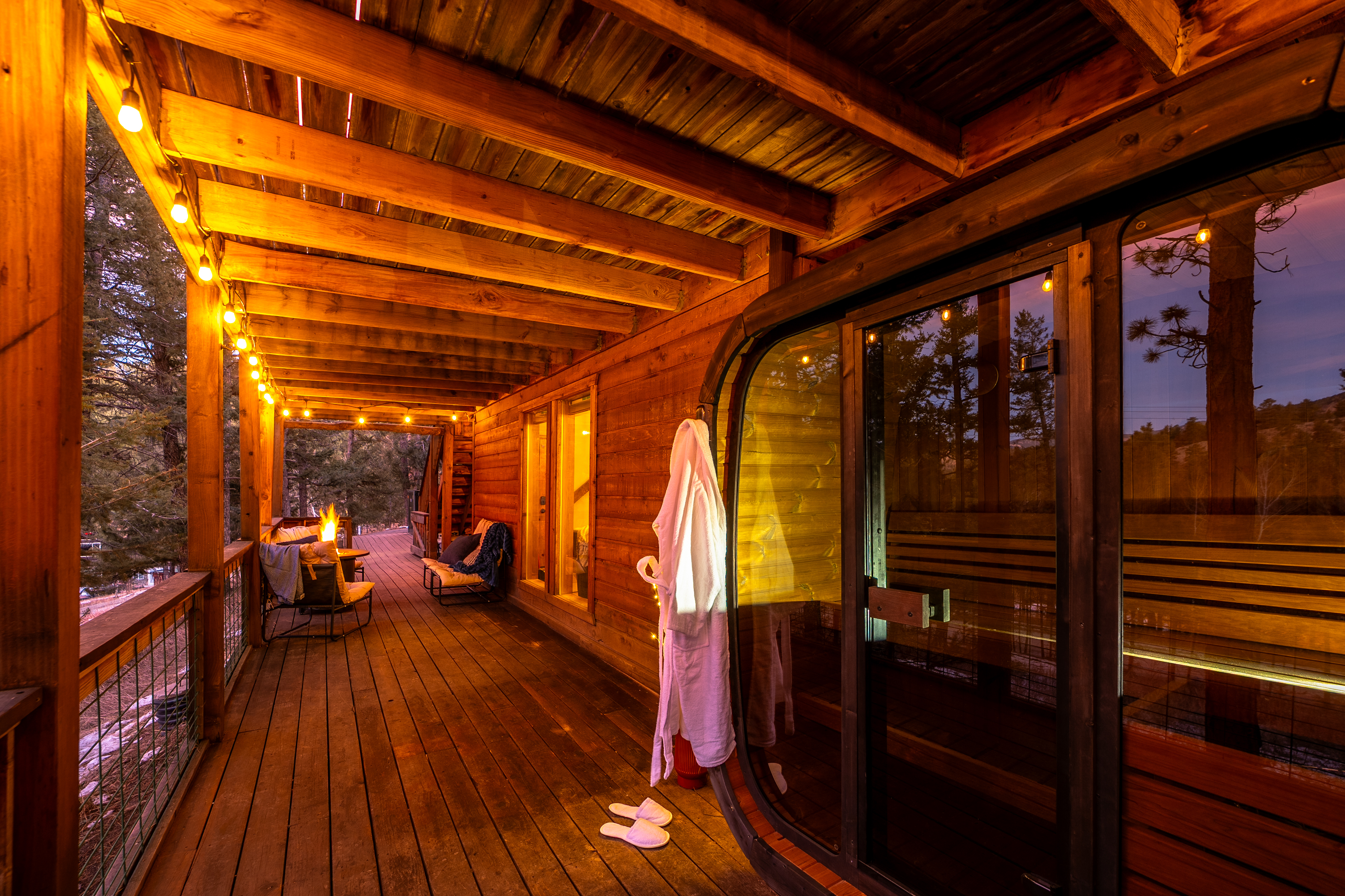 ✨🔥 Covered deck nights done right—string lights, cozy lounge seating, a crackling firepit, and your private sauna 🧖‍♂️🌲 for the ultimate mountain unwind.