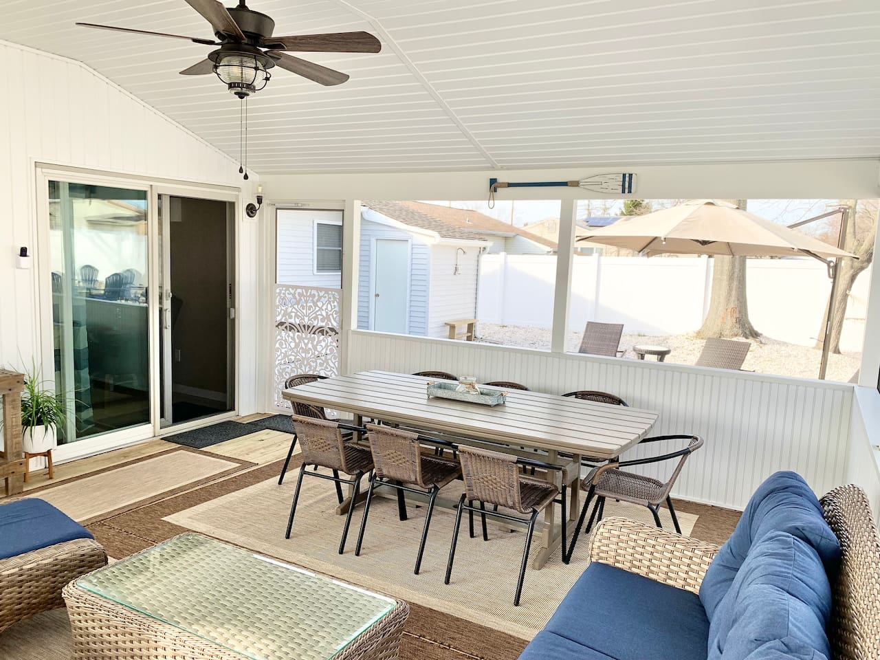 Experience the best of indoor-outdoor living in our screened-in sunroom. Kick back on navy wicker seating to watch the game or enjoy a meal at the large dining table—all while staying protected from the elements in a bright, coastal setting.