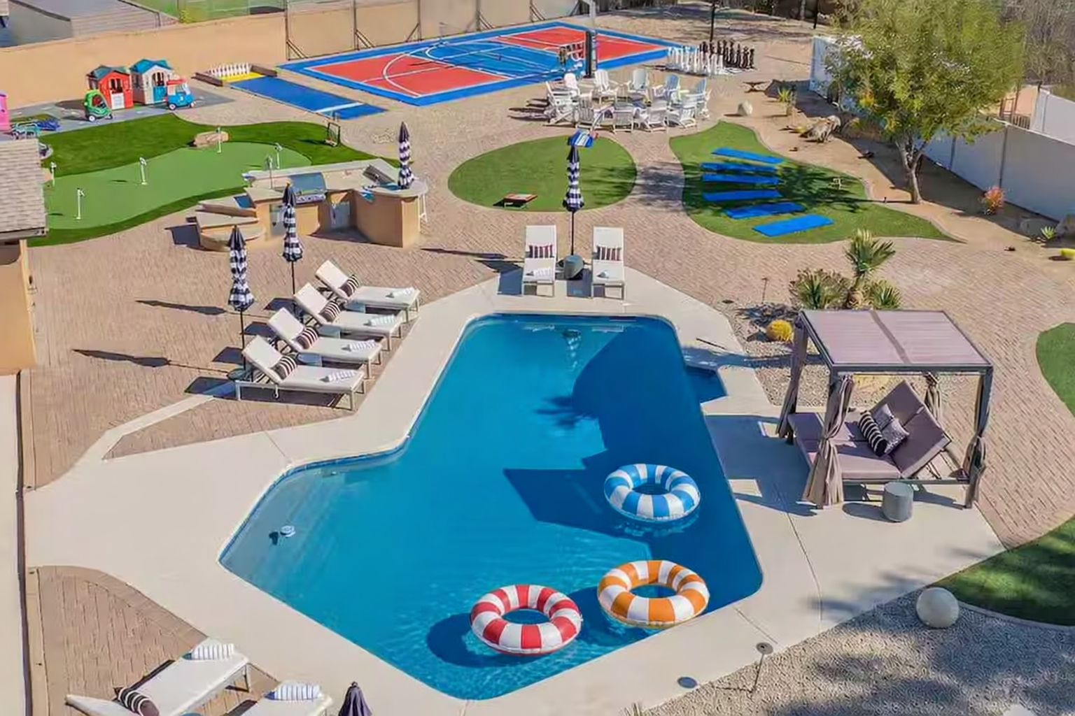 Expansive private backyard with heated pool, pickleball court, volleyball, basketball, mini golf, and a cozy firepit — perfect for large groups and family fun in Scottsdale.