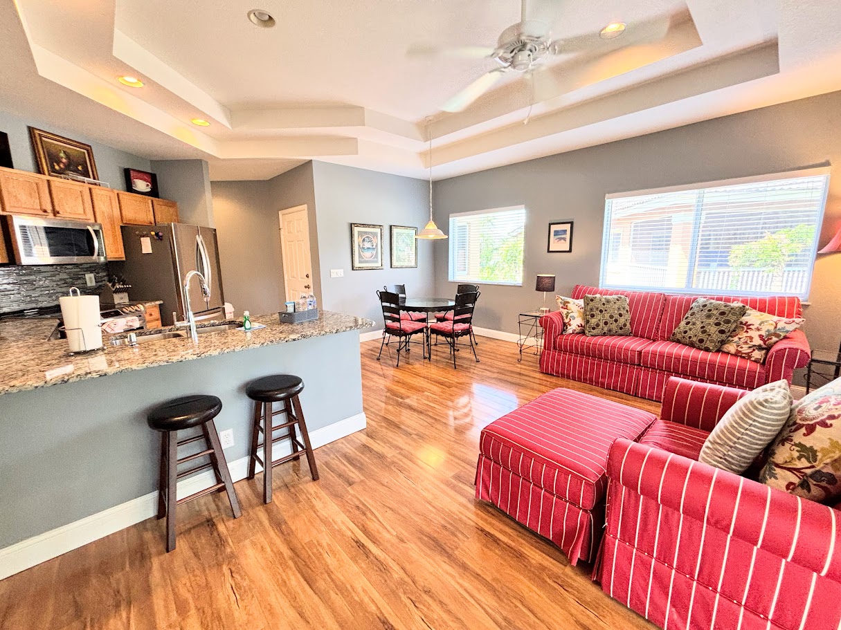 Open kitchen and living space with breakfast bar seating, updated flooring, and a bright, welcoming layout.