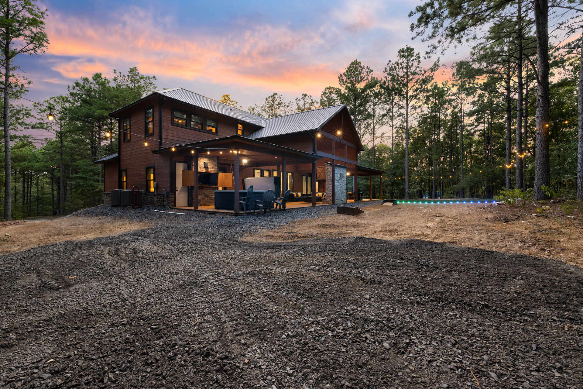 Beautiful cabin exterior surrounded by nature with a wide, convenient parking area for multiple vehicles.