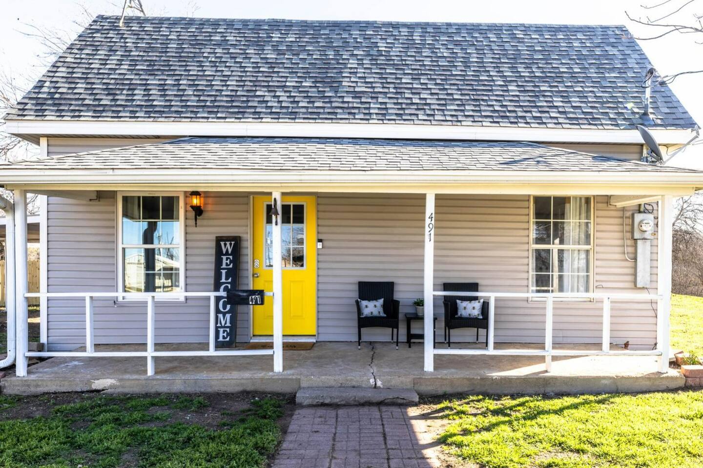 The bright and welcoming front porch invites you in with its vibrant yellow door, creating a cheerful first impression.