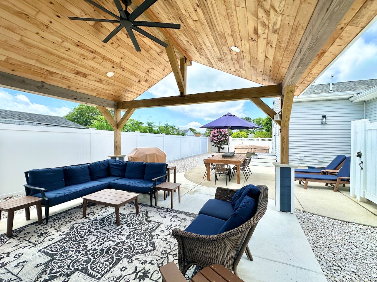 Relax under this impressive wooden pavilion, featuring navy sectional seating and a patterned rug. The space overlooks the hot tub, outdoor dining area, and professional grill for all-day entertainment.