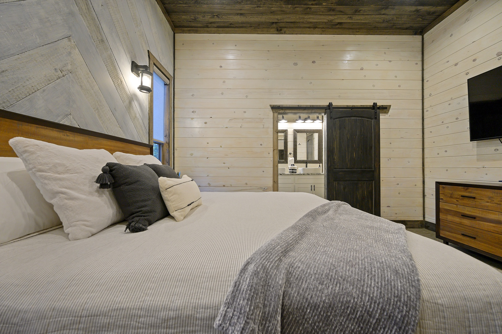 Comfort meets clean design. Soft bedding, sturdy wood accents, and gentle light make this room an instant exhale.