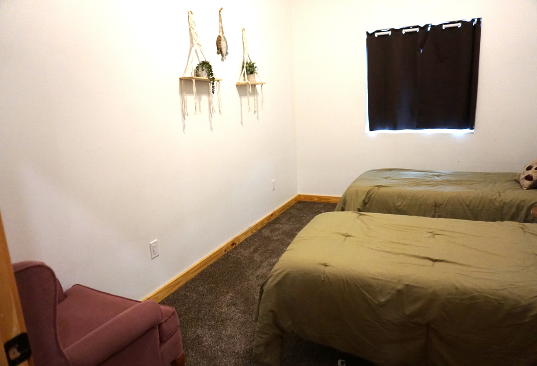 Another view of bedroom 2 with 2 twin beds and a chair. 