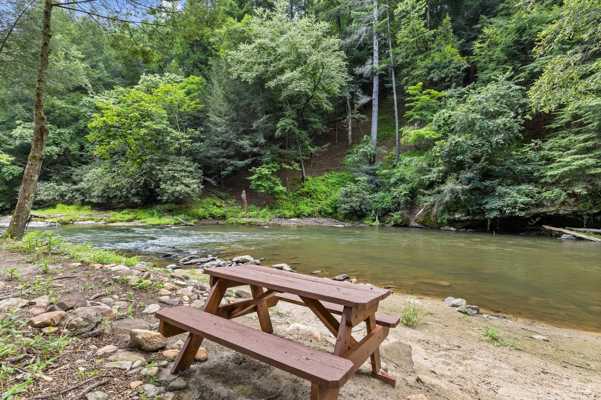 The property's sandy shoreline is perfect for relaxing, skipping rocks, or enjoying a riverside picnic.