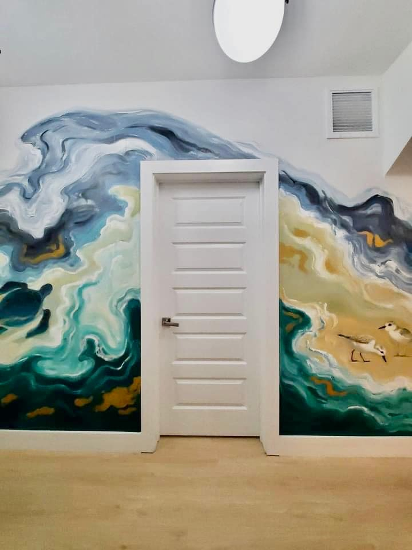 The mural carries upstairs too, wrapping the landing wall in green water and pale sand, with two sandpipers working the tideline. Small hands will find them first, though you will notice them by the third day.