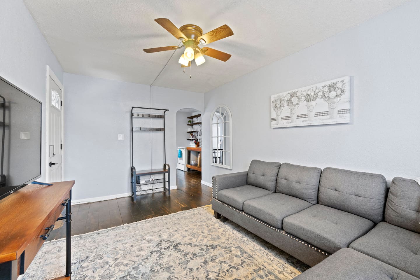Cozy living room featuring a grey sectional, a convenient coat rack, and a TV for relaxation and comfort.