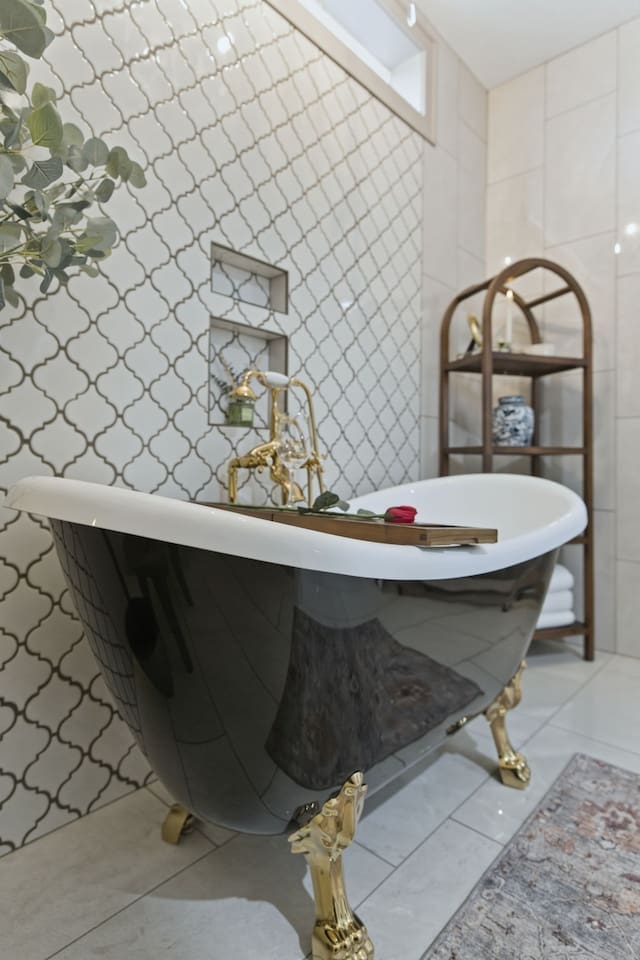 Stylish clawfoot tub with gold detailing, set against elegant patterned tiles for a relaxing and refined soak

