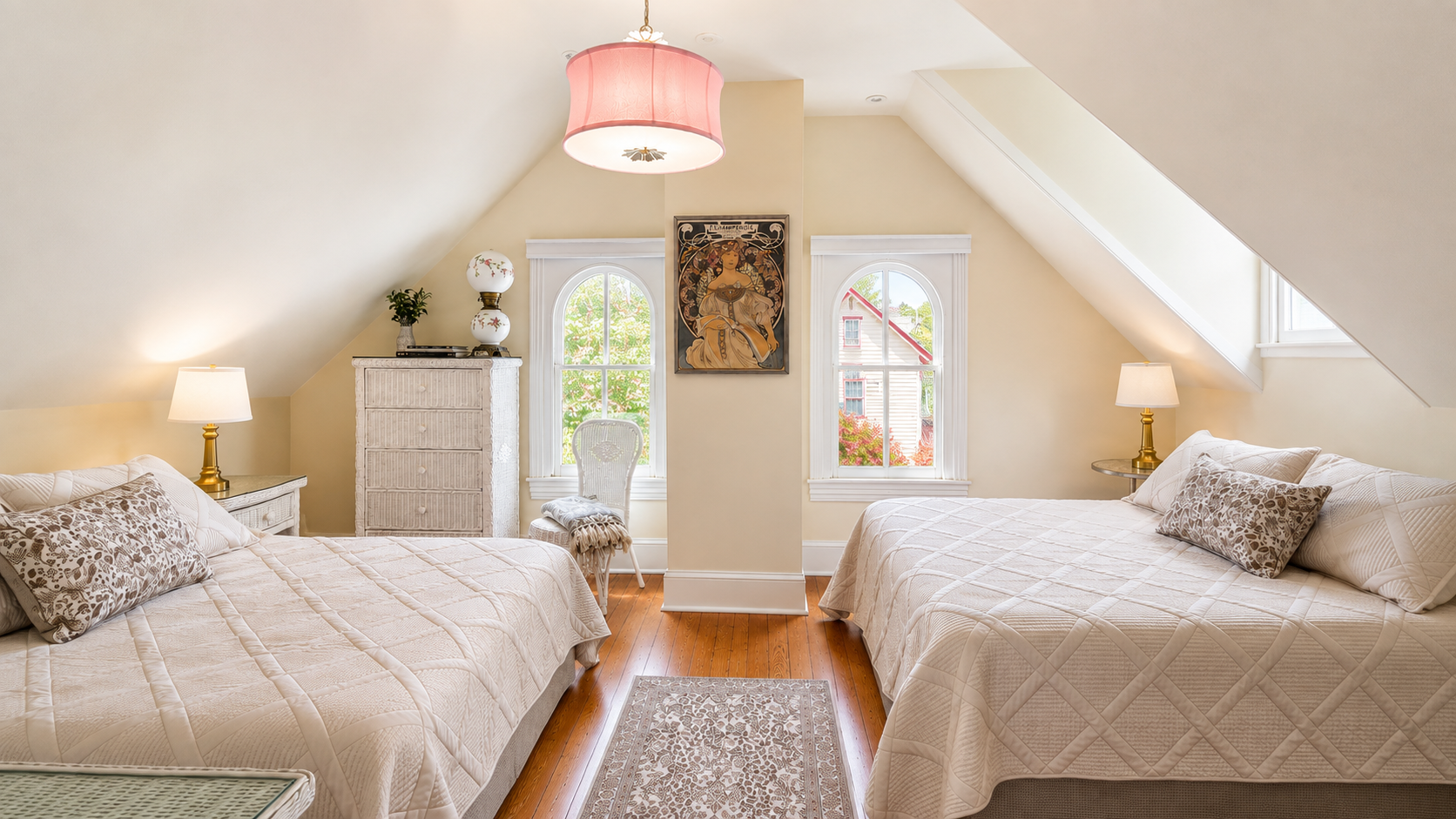 The third floor queen bedroom — vaulted ceilings, arched windows, and an Alphonse Mucha print that looks like it’s always lived here.