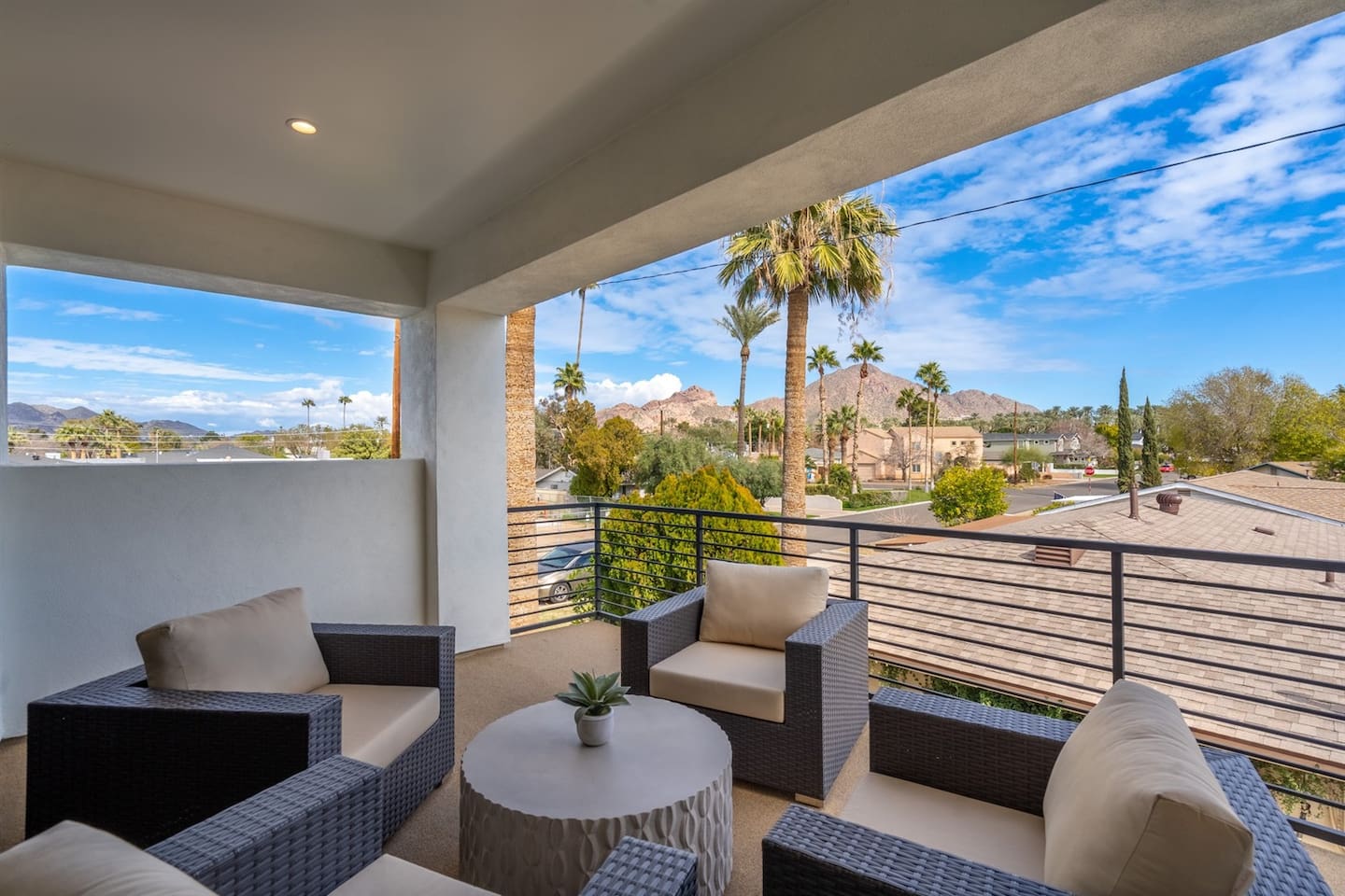 The balcony offers a breathtaking view of Camelback Mountain, with its rugged peaks beautifully framed by the clear sky. A charming set of tables and chairs invites you to sit back and soak in the stunning scenery.