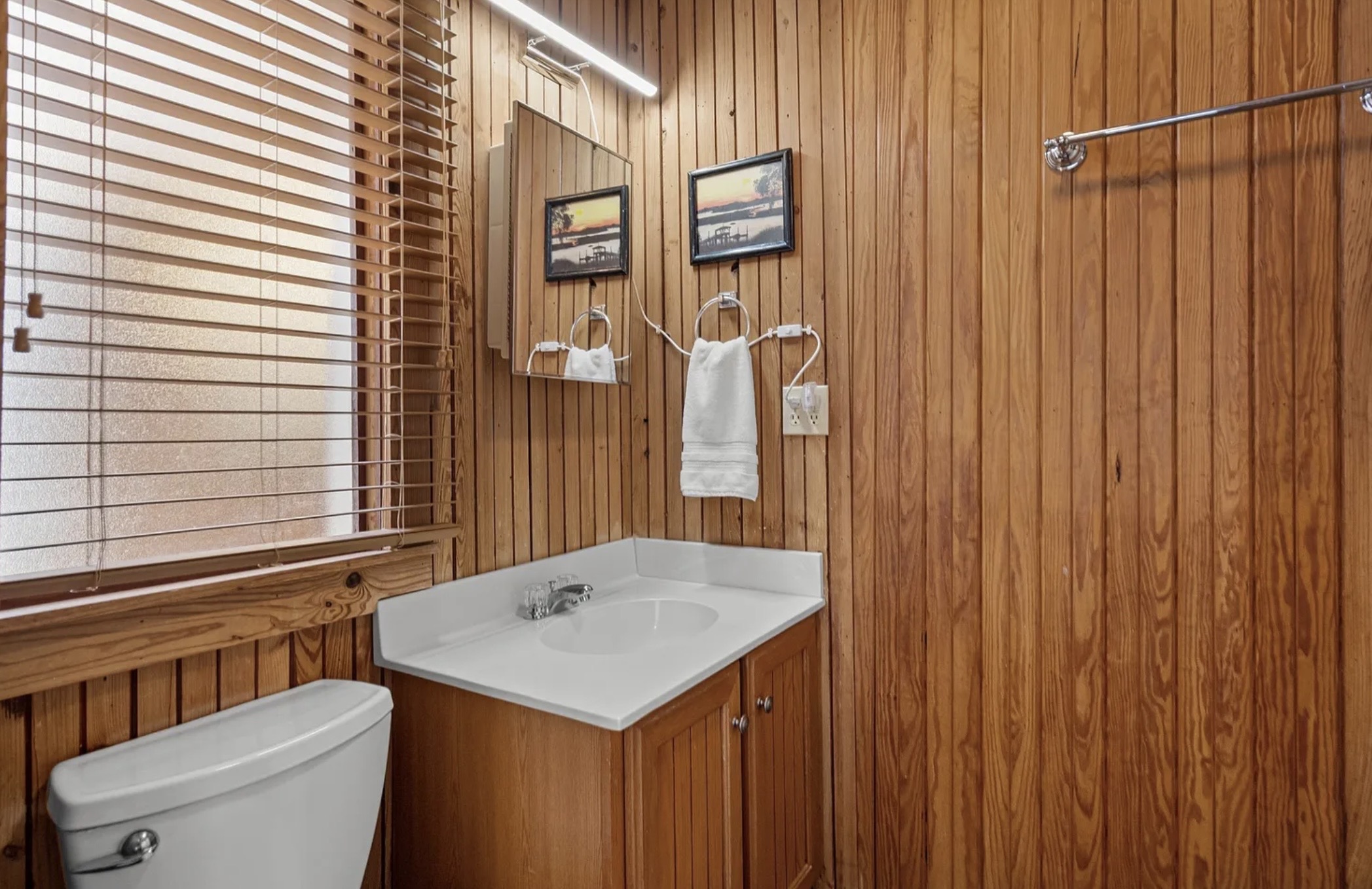 Warm wood details give the upstairs bath a cozy, classic beach house feel. ⭐