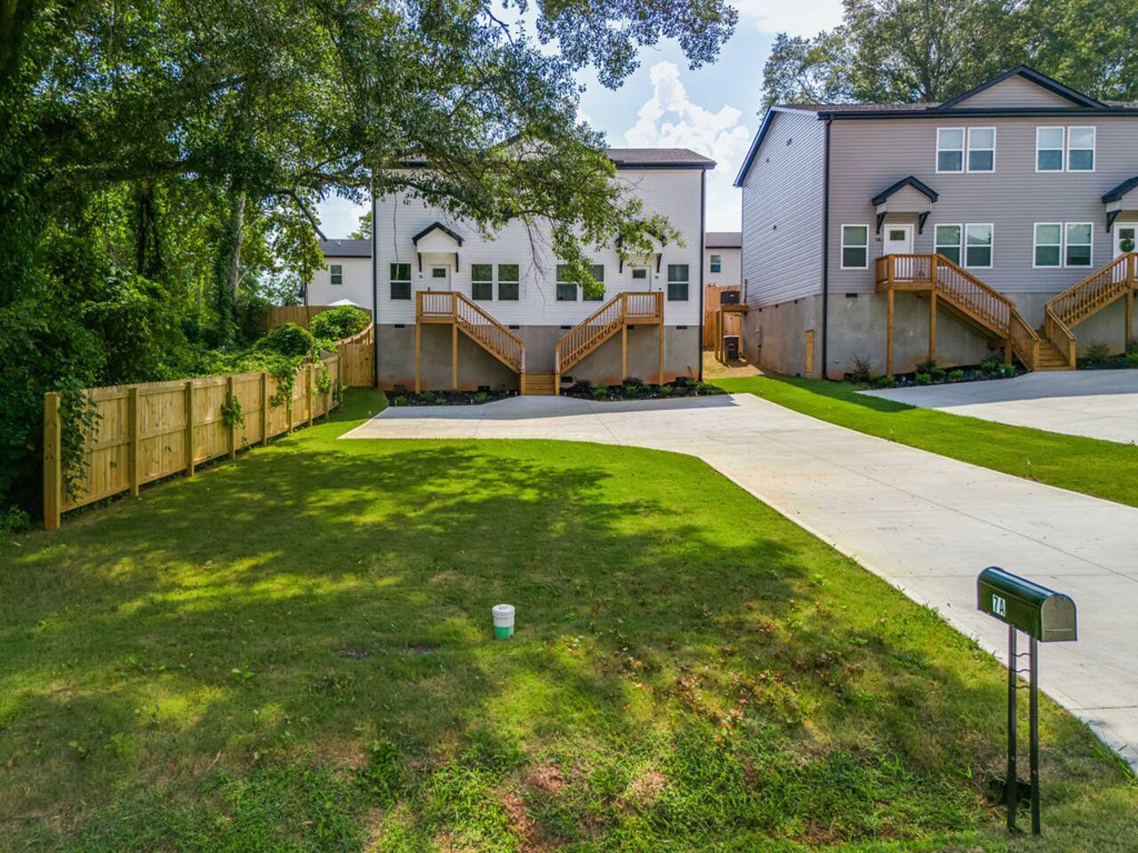 Enjoy the front yard with vibrant green grass, a driveway, and a cement parking pad for easy and convenient parking."