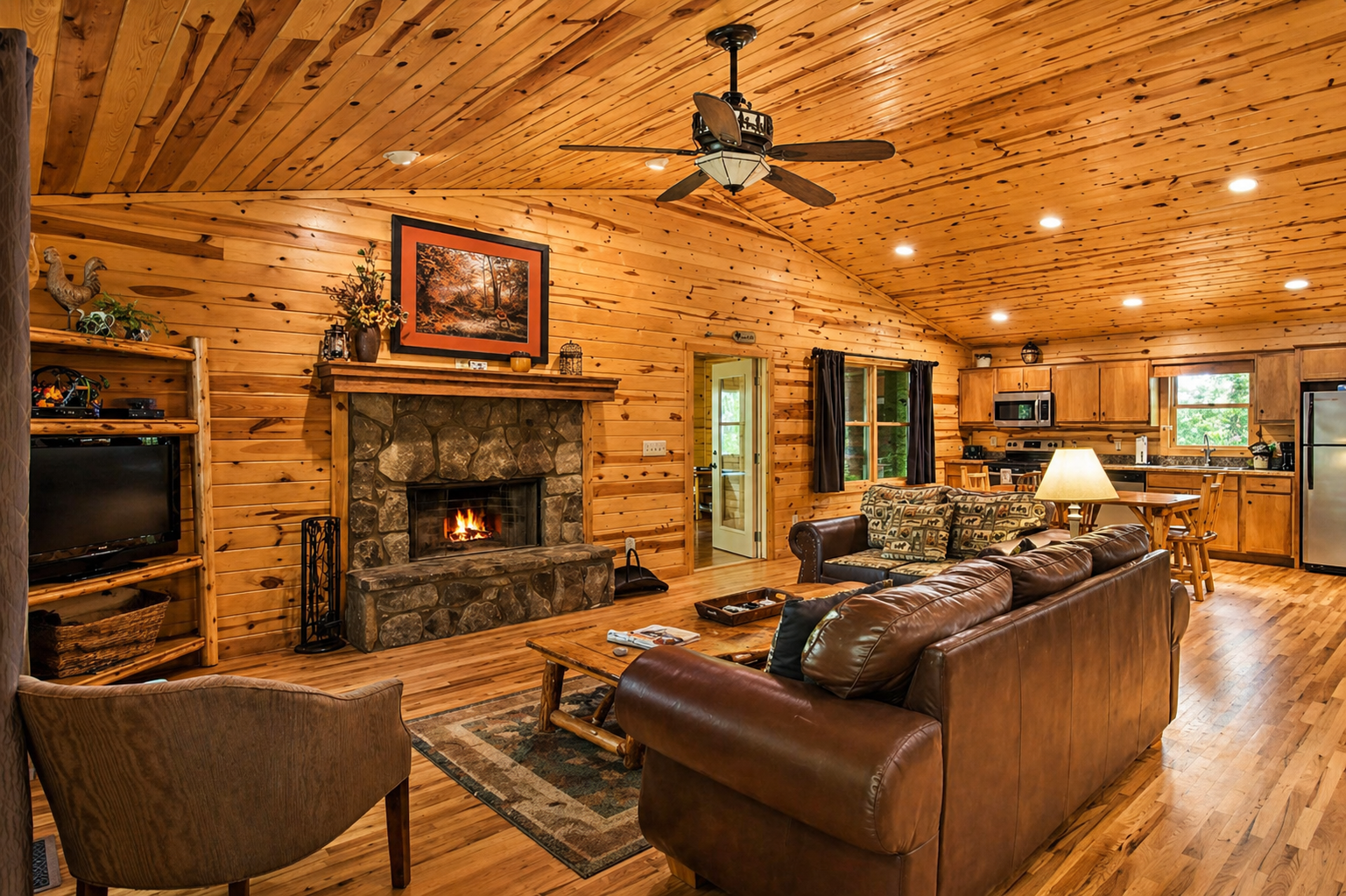 Warm, inviting cabin living with a stone fireplace, vaulted wood ceilings, and an open-concept space perfect for relaxing or entertaining.
