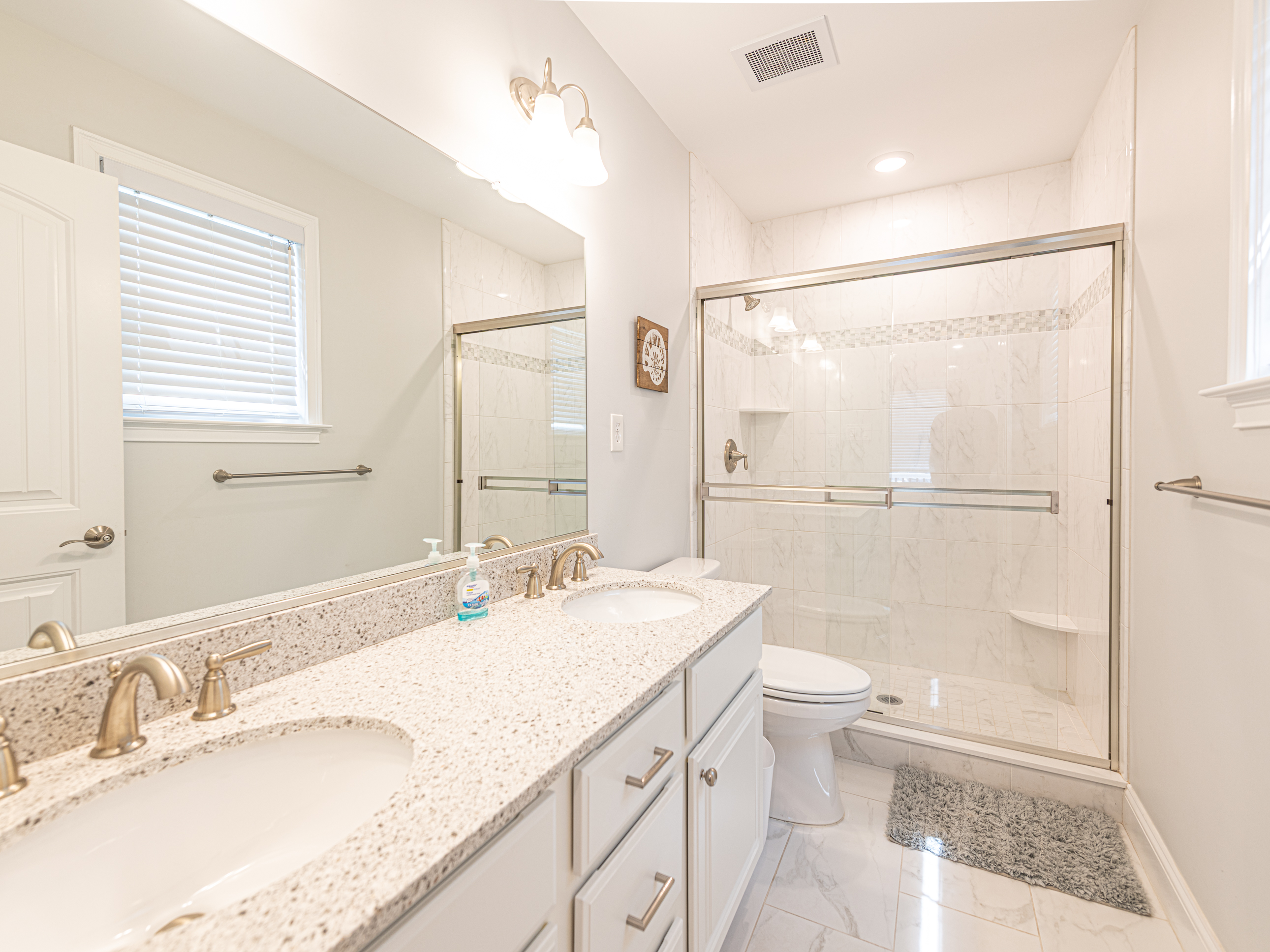 Primary bathroom with double sink vanities and tiled shower