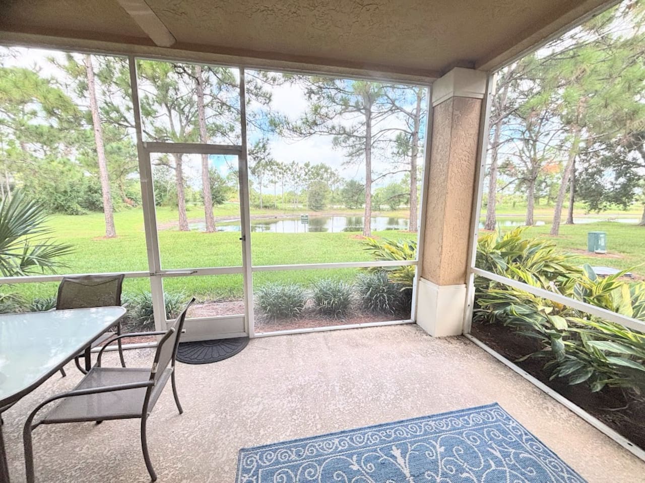 Private screened patio with outdoor seating and peaceful views of the surrounding green space.