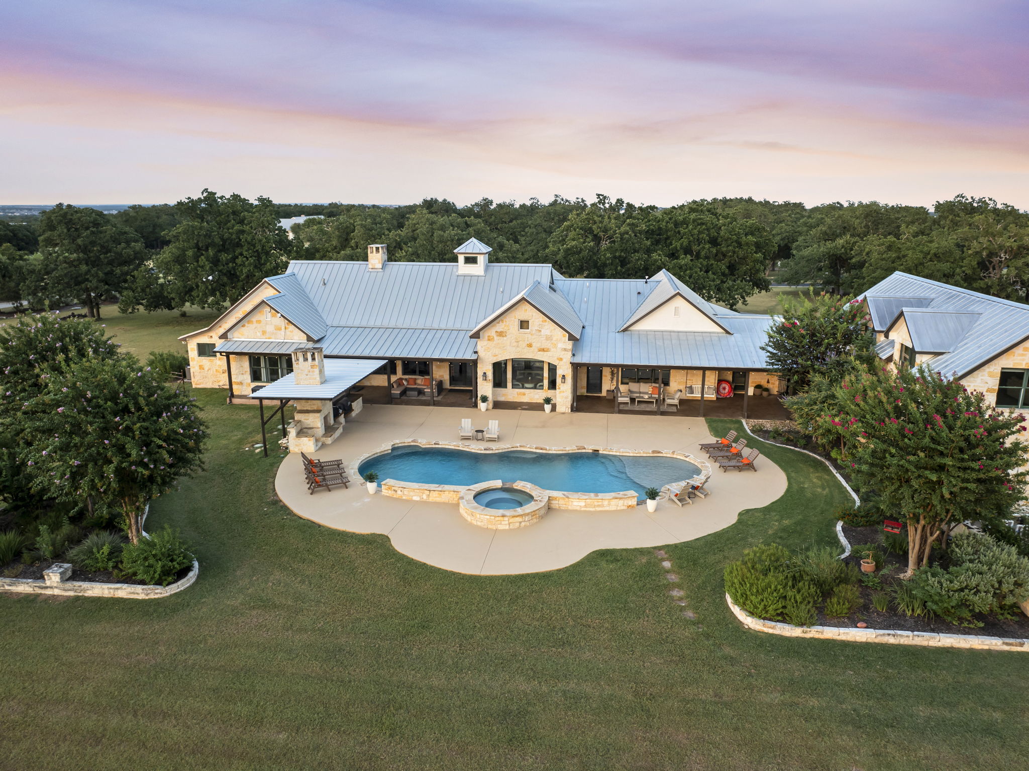 Bird's-eye perspective of a beautiful home and its expansive grounds, featuring a sparkling swimming pool and hot tub.