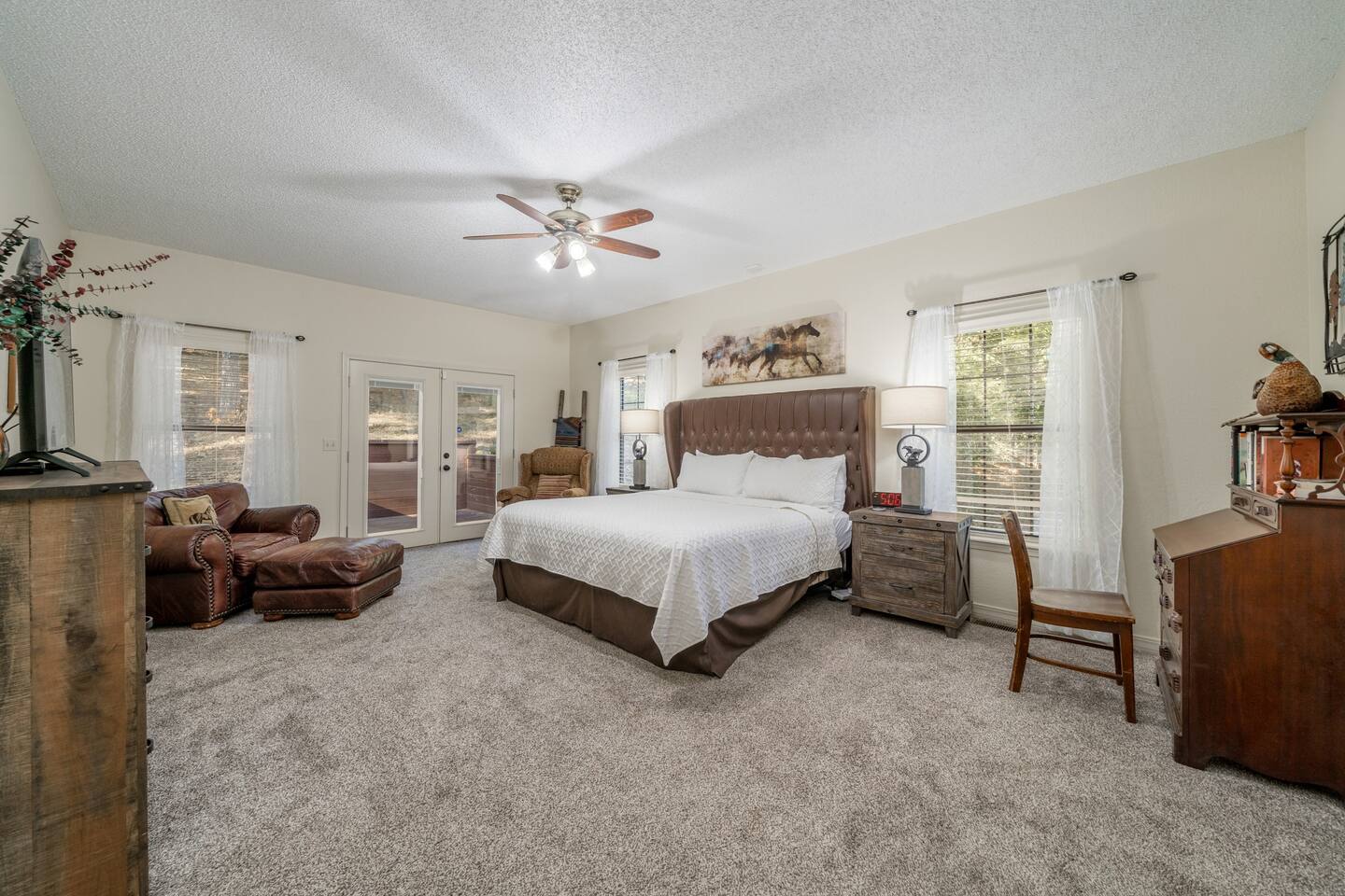 King bed situated beneath galloping horses, luxurious linens and pillows atop a wonderful comfortable mattress. Smart TV, beautiful antique desk, and comfy chairs to relax in. Has private lavatory, and back deck access via french doors. -Master Bedroom