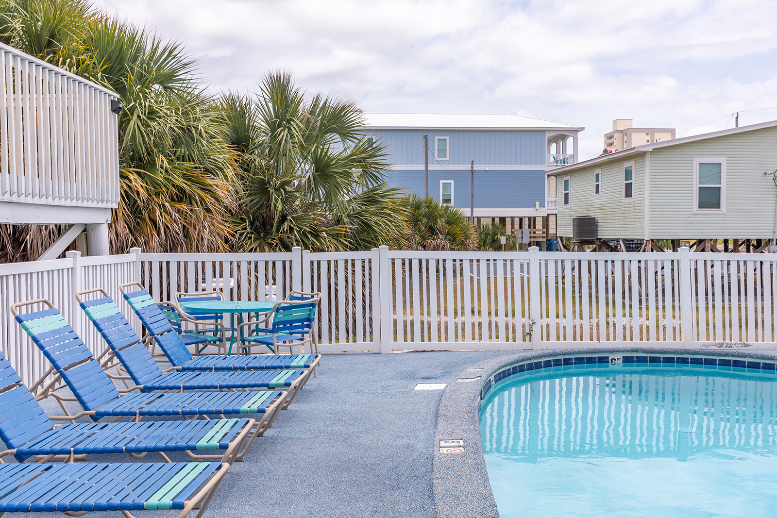 The shared pool is tucked behind fencing and palms, with loungers and tables set on a rubberized deck that’s easy on bare feet. A simple, comfortable spot to cool off or spend a quiet afternoon outdoors.