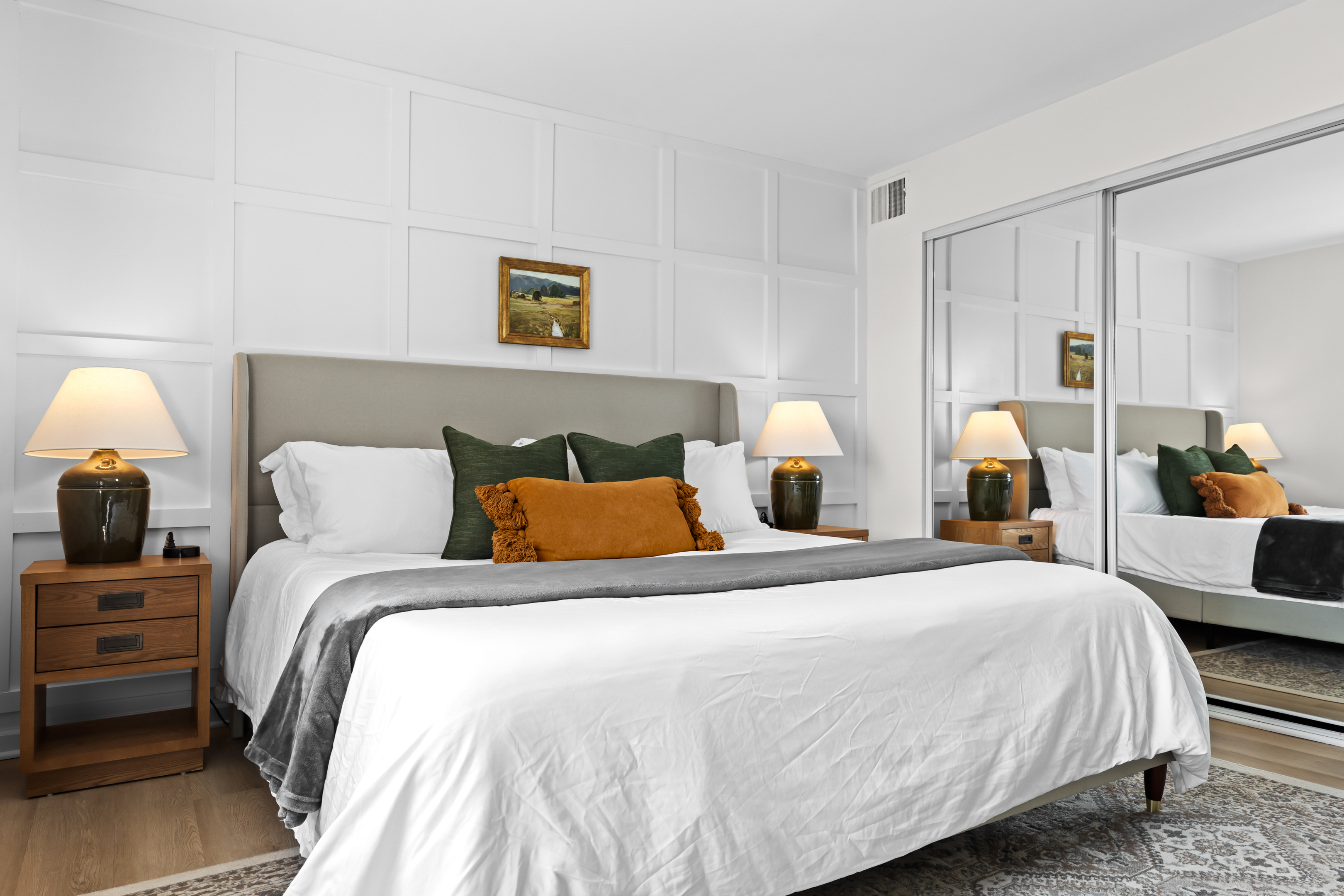 Spacious bedroom with a king bed, mirrored closet doors, and warm lighting.