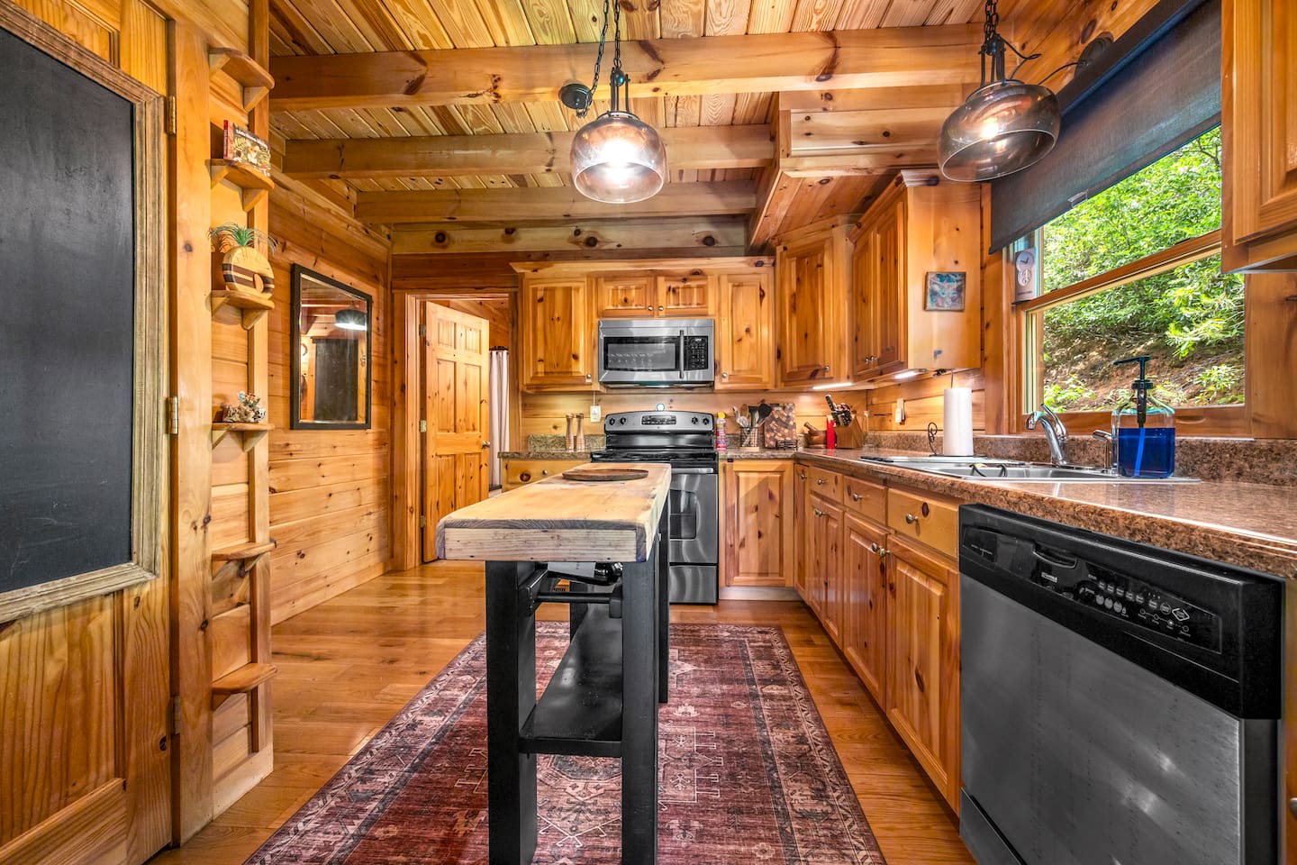 Charming cabin kitchen with warm wood interiors, stainless steel appliances, and a spacious prep island.