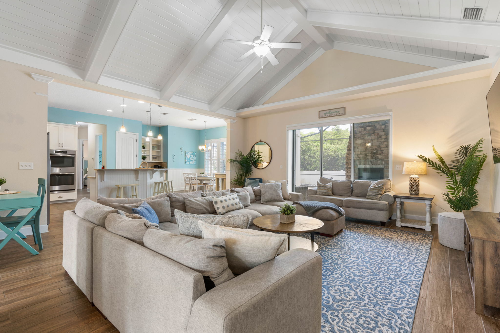 After the beach, toss open the sliders, settle into the oversized sectional, and let the whole house come together—snacks at the island, a movie in the living room, and the glow of the outdoor fireplace just beyond the glass.