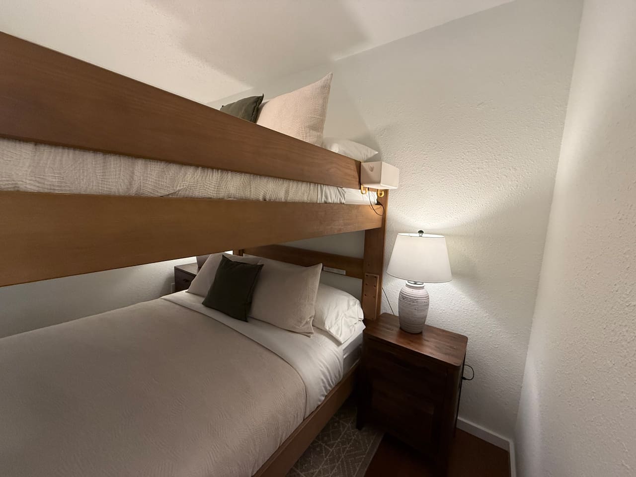 The main floor bedroom features a unique adult bunk bed with a queen-size mattress on both the top and bottom bunks, comfortably sleeping four adults. This layout is designed to maximize space without sacrificing comfort. 