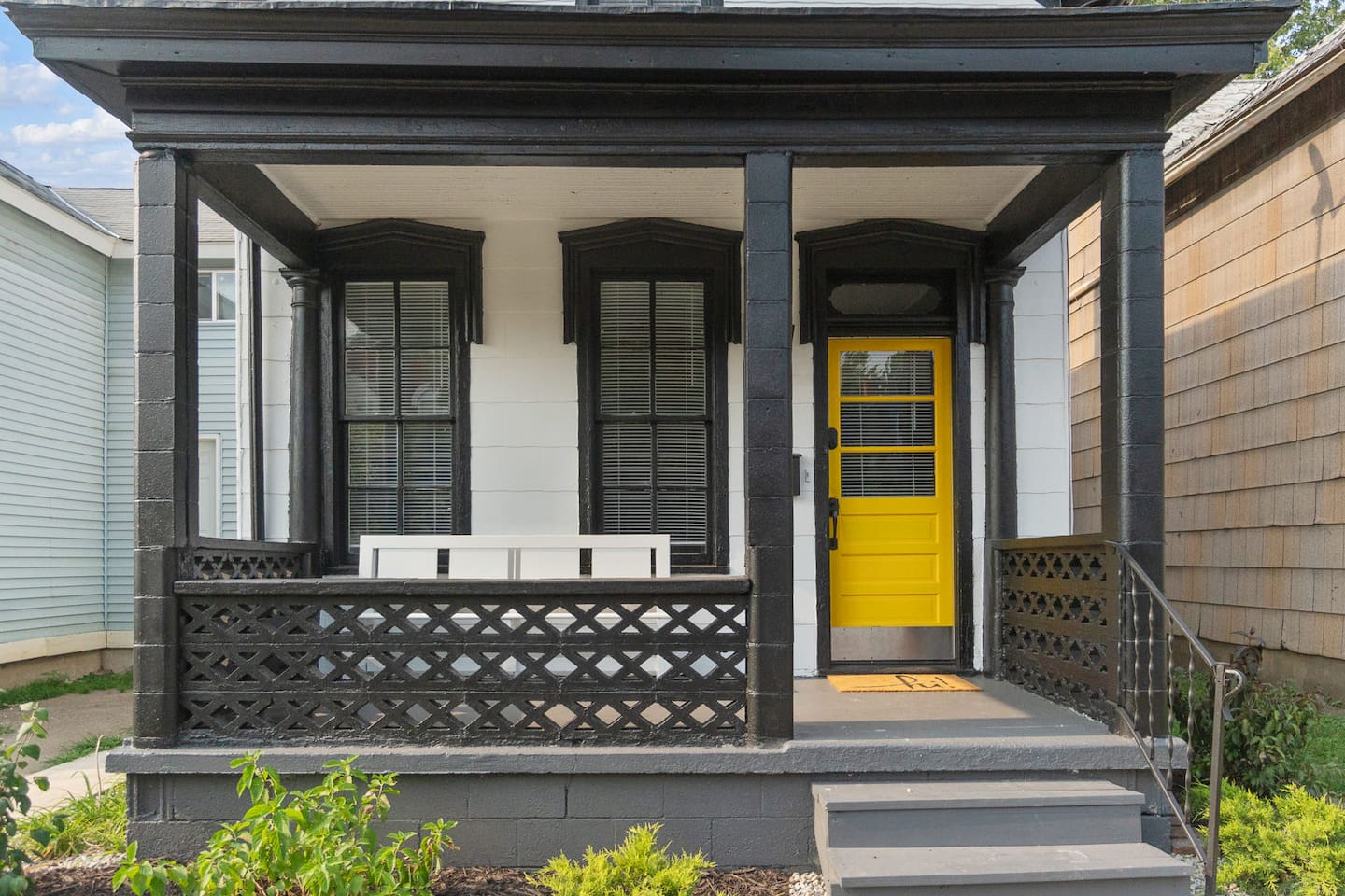 Front porch with a vibrant yellow door, adding a cheerful and welcoming touch to the entrance, surrounded by well-maintained landscaping.